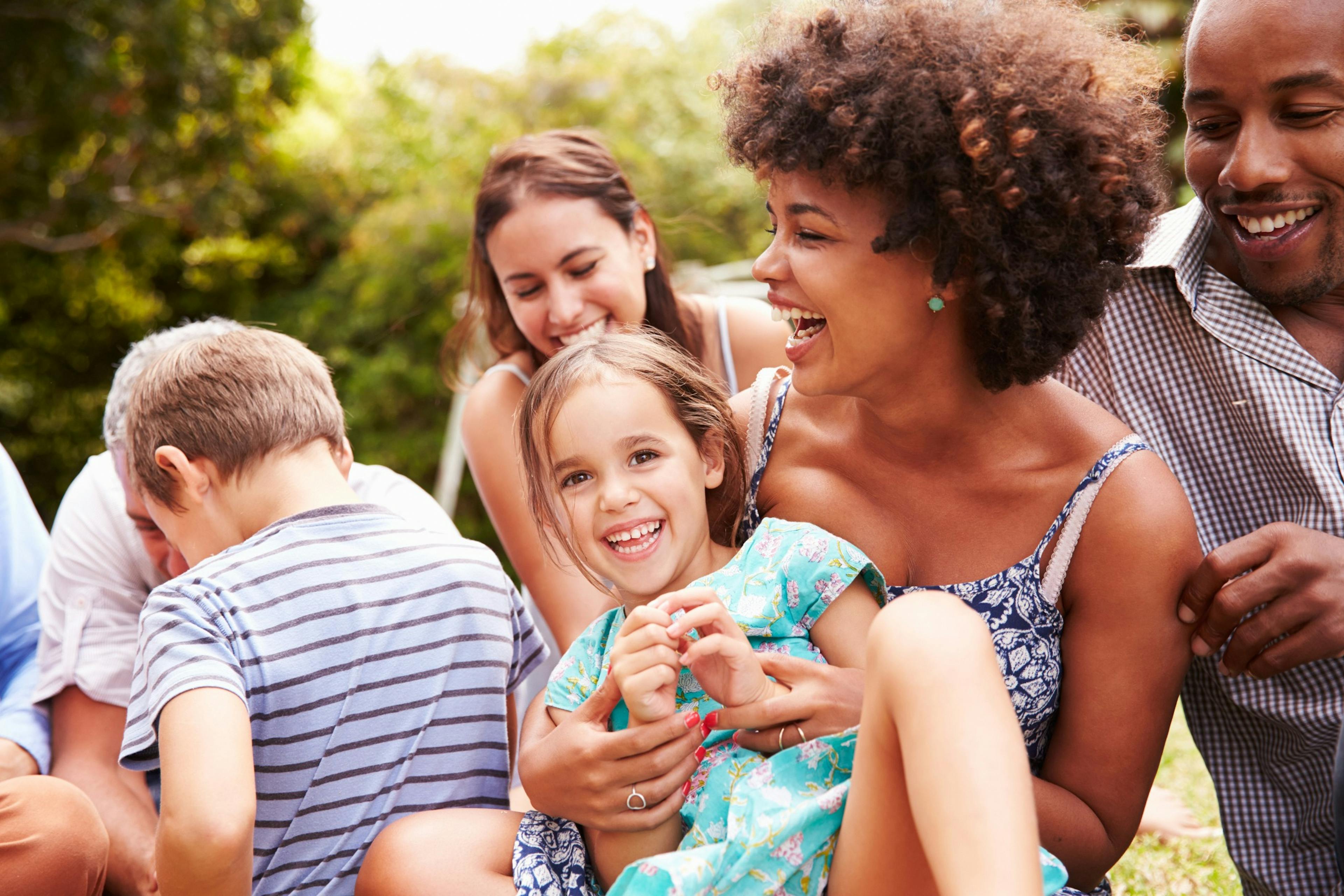 Adults and kids on the grass laughing.