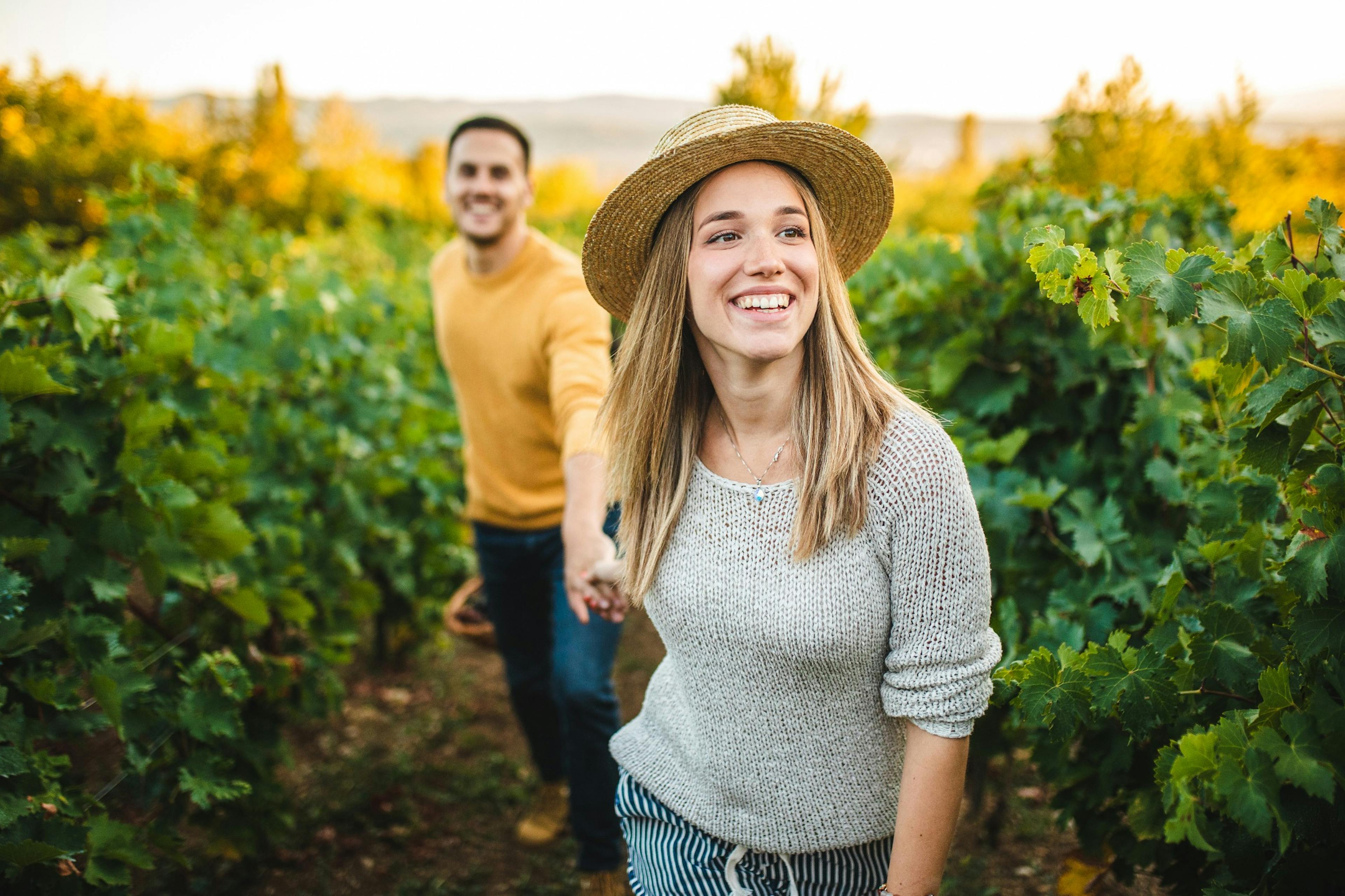 woman leading man through a vineyard