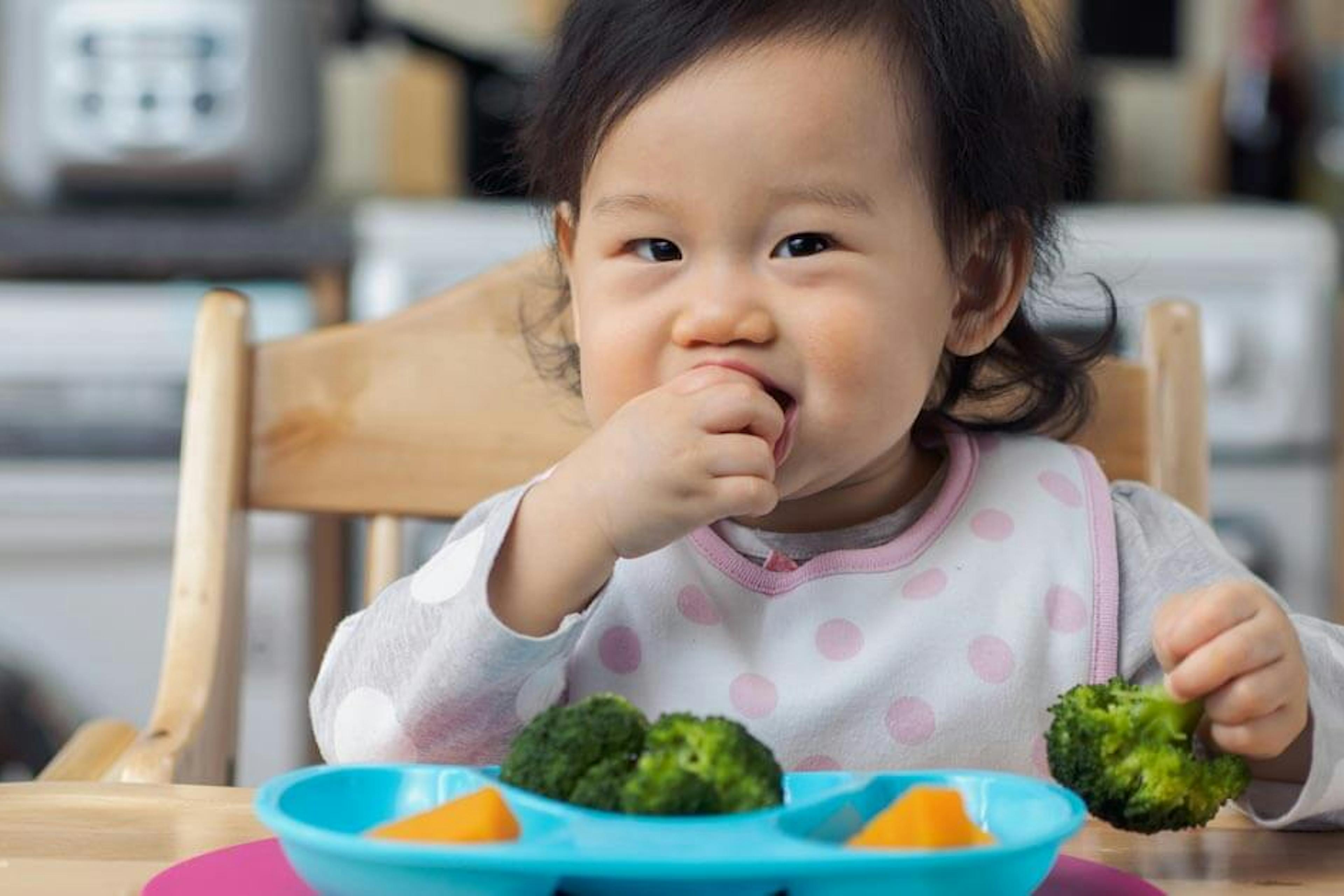 baby girl eatting broccoli