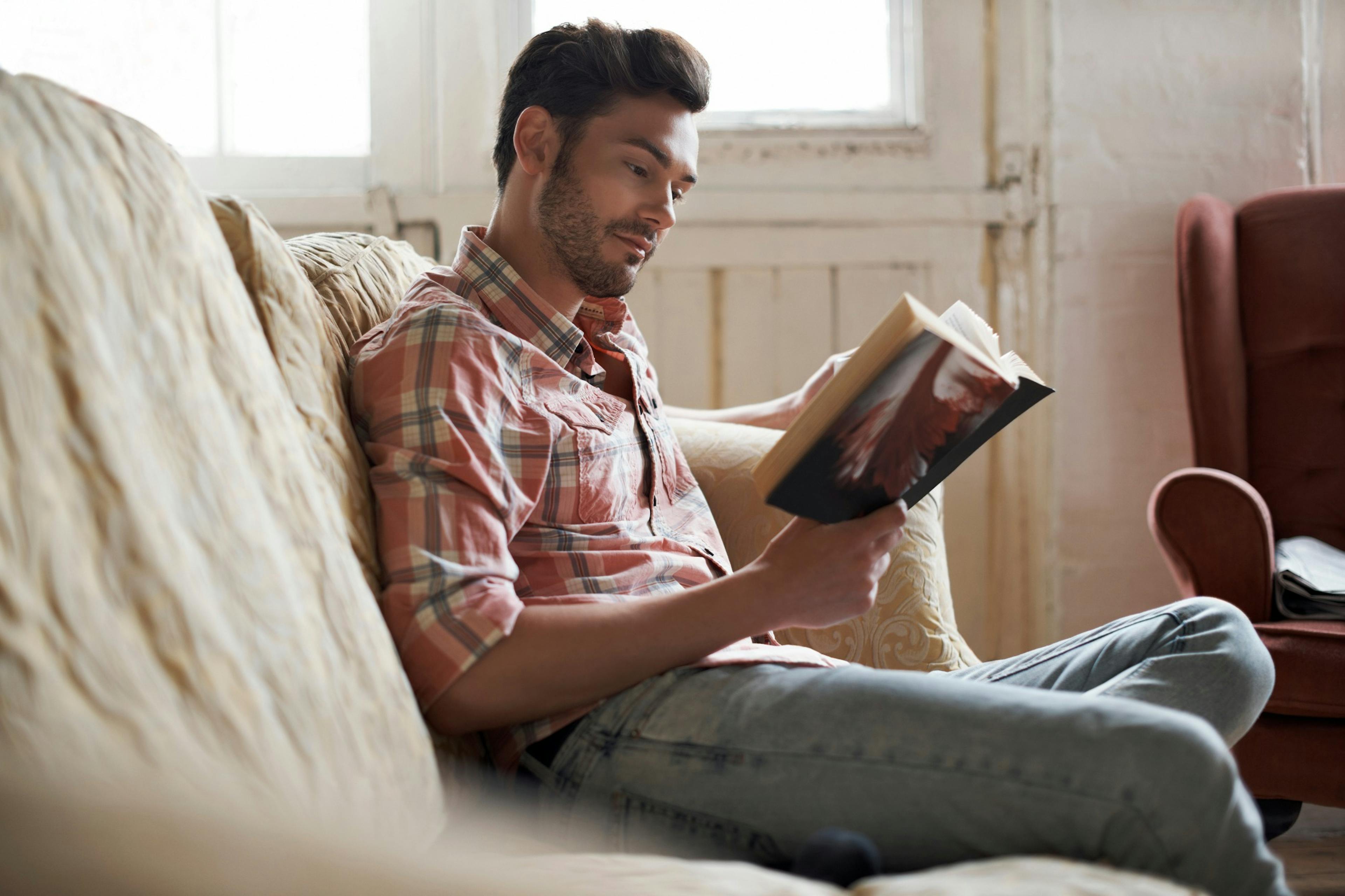 man sitting on couch reading