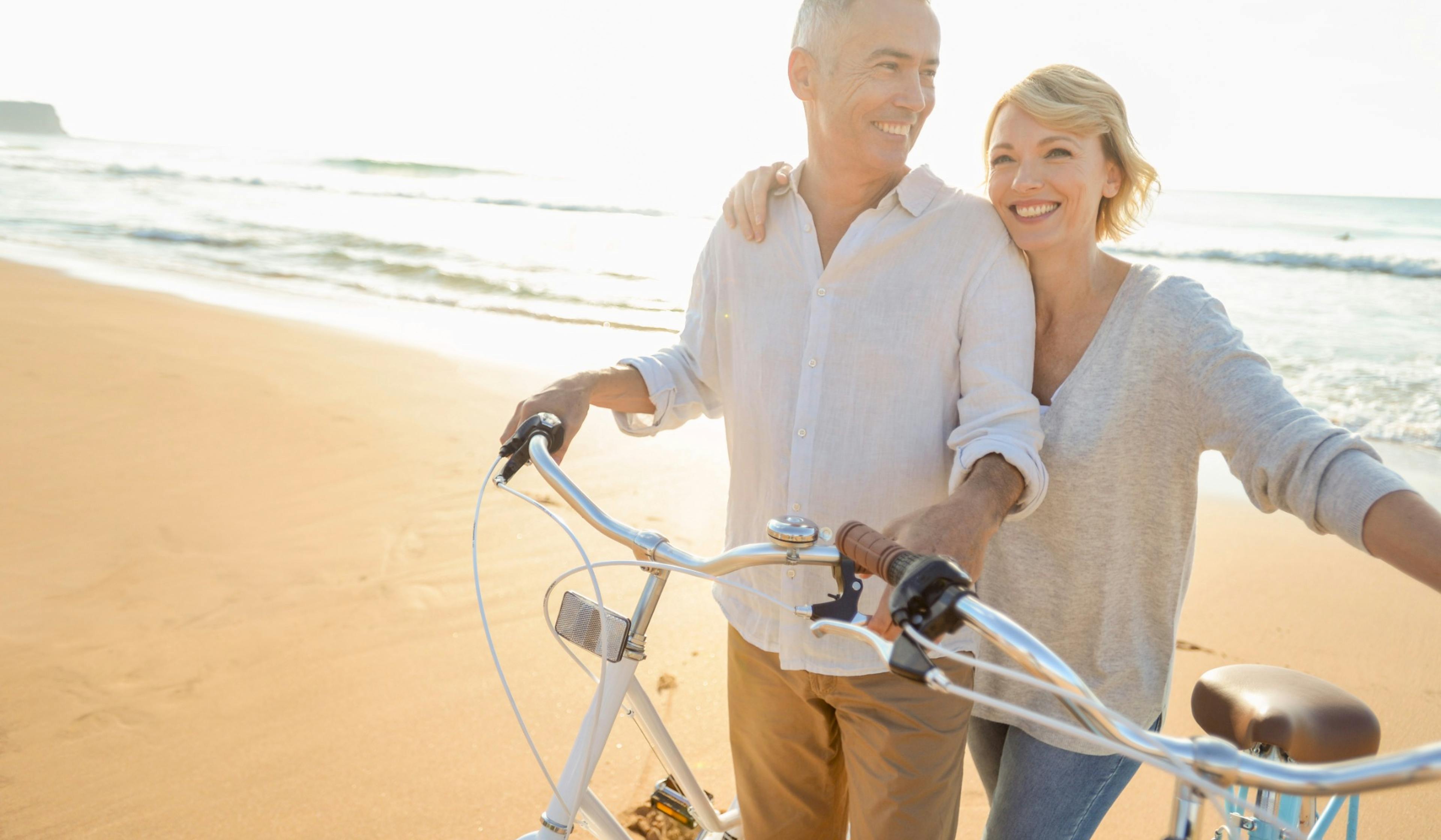 mature older couple on the beach riding bikes