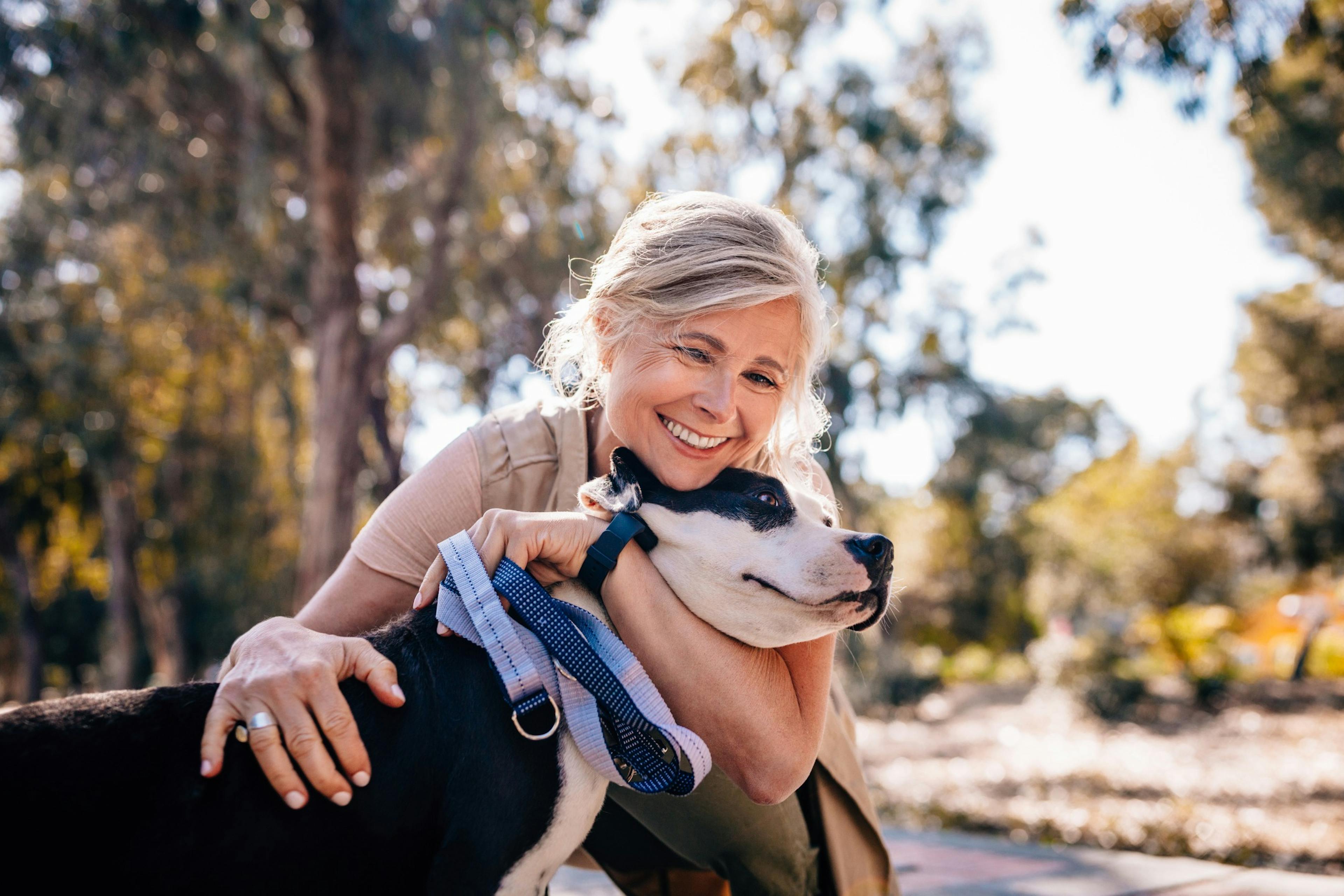 mature, happy woman hugging a dog