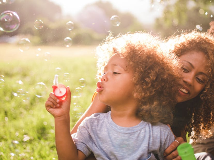 young boy and mom blow bubbles outside.