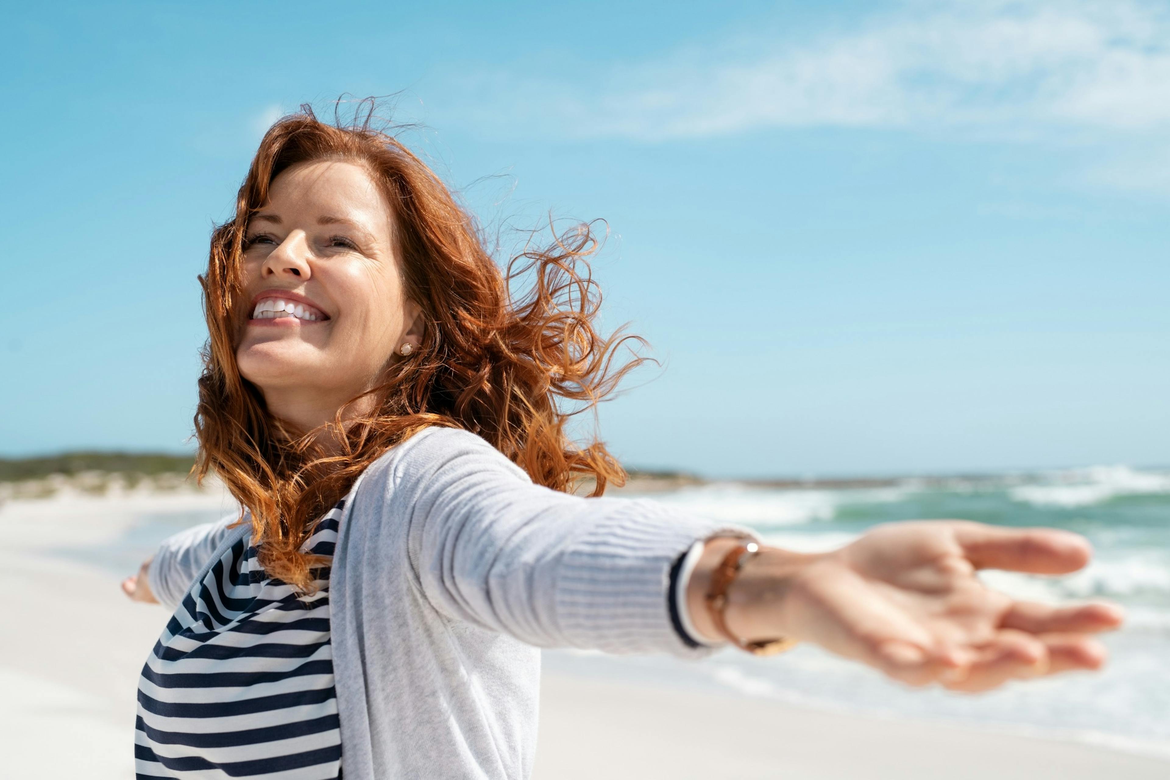 mature woman enjoying the breeze on the beach