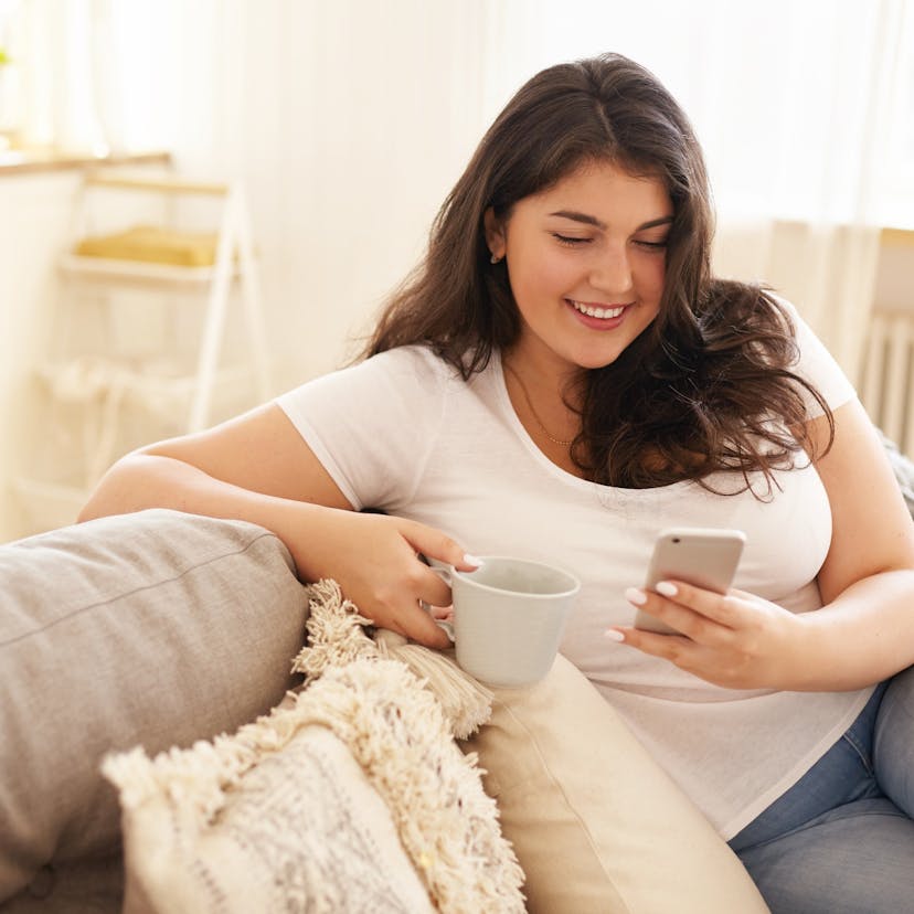 Heavier woman using phone and drinking coffee