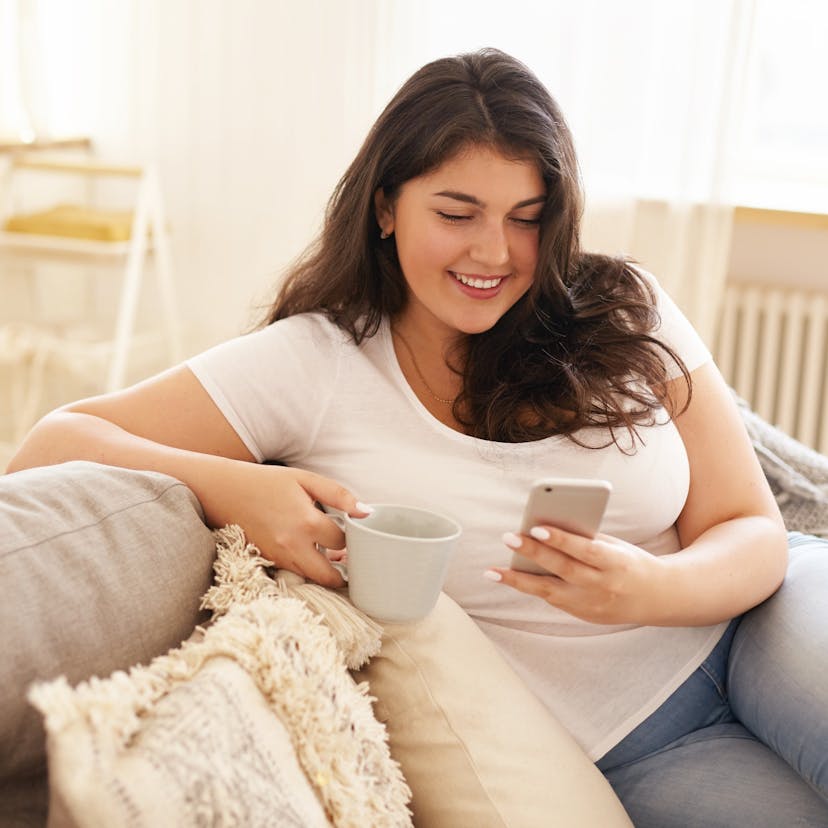 Heavier woman using phone and drinking coffee