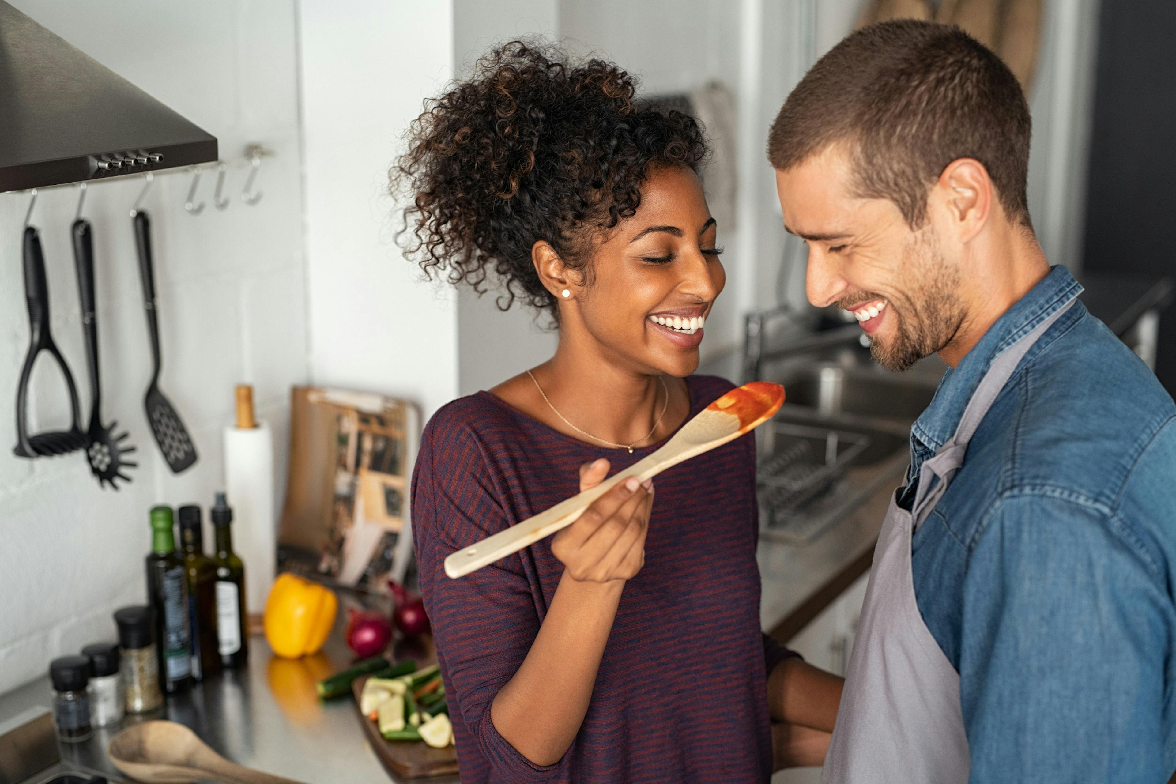 Couple testing sauce in the kitchen. 