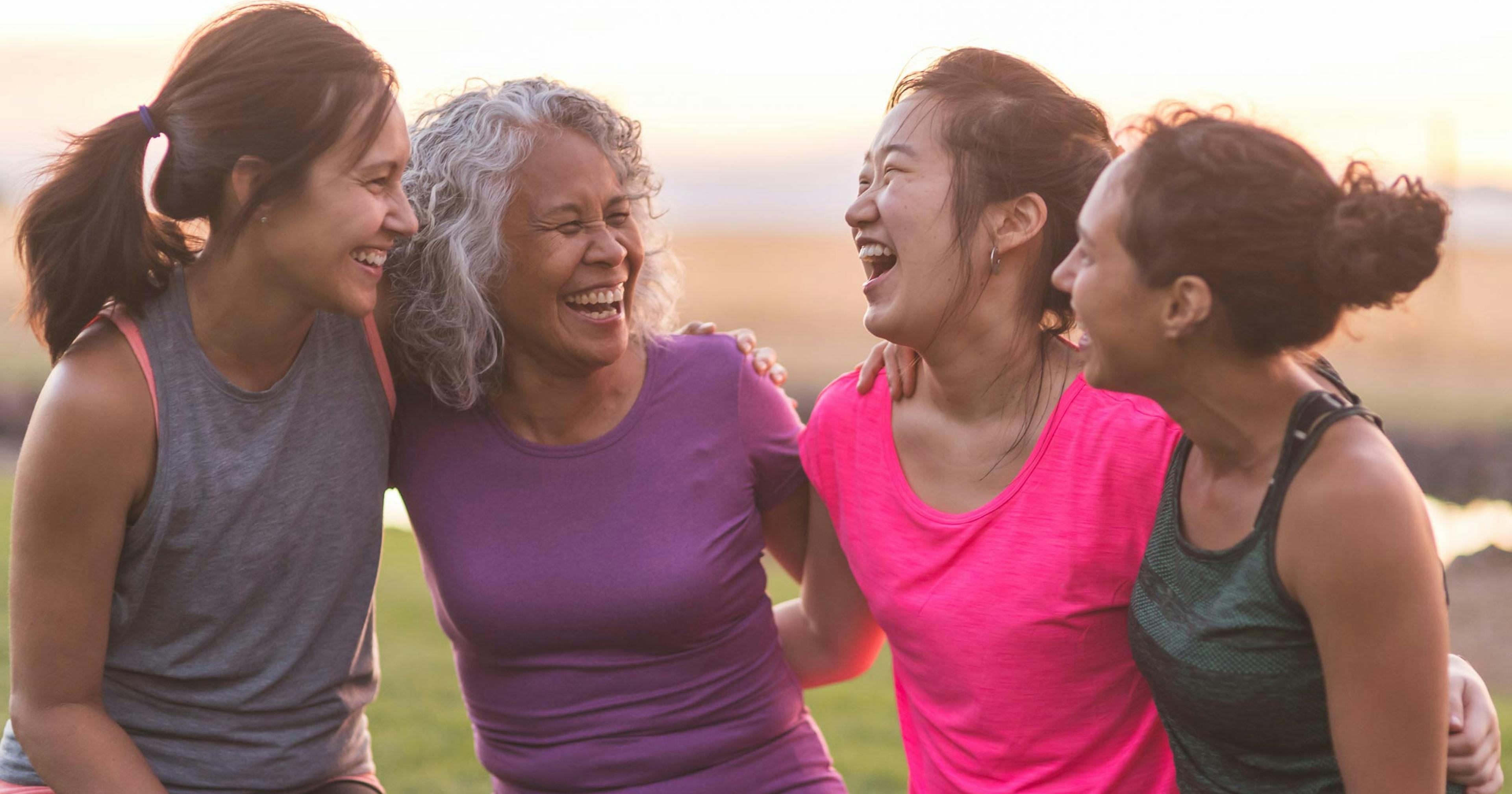 four women laughing together after a workout