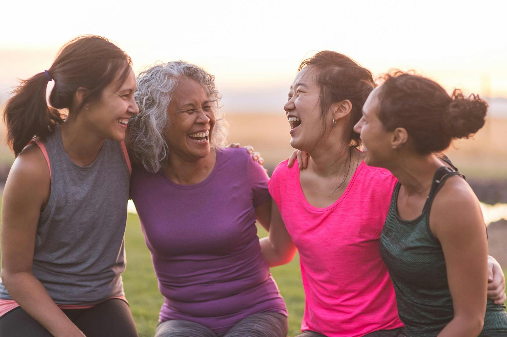 four women laughing together after a workout