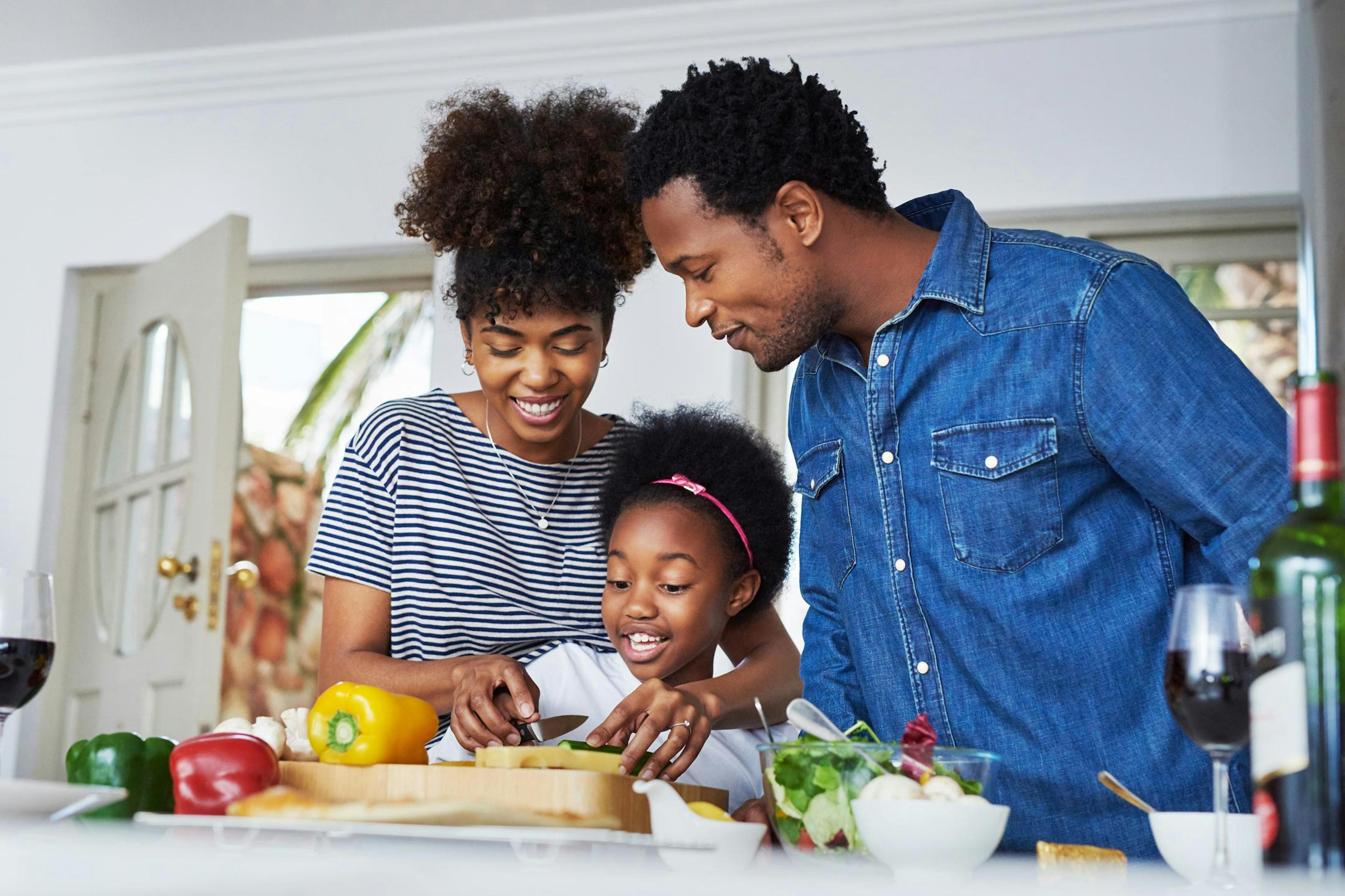 mom and dad teaching daughter how to cook