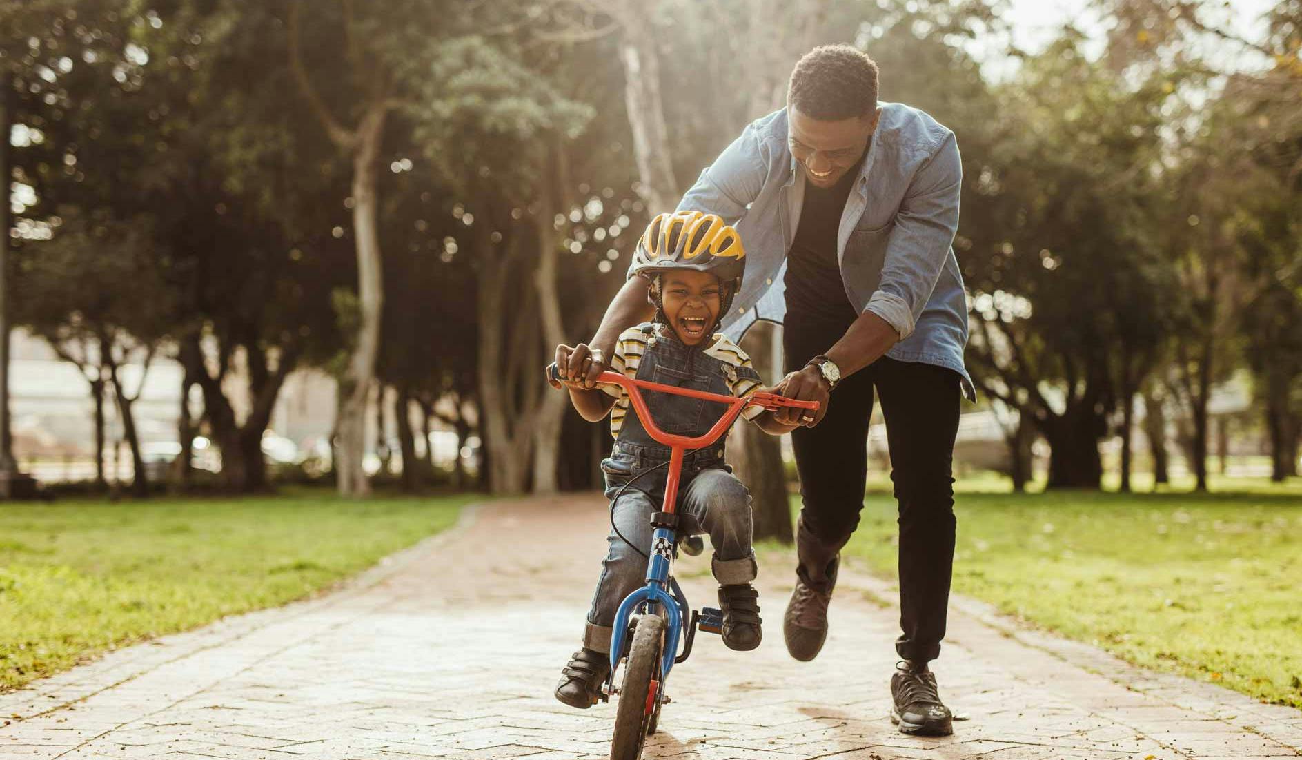 dad teaching son to ride a bike