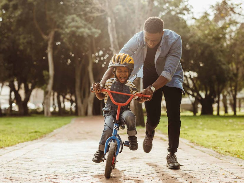 dad teaching son to ride a bike