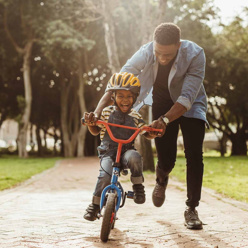 dad teaching son to ride a bike