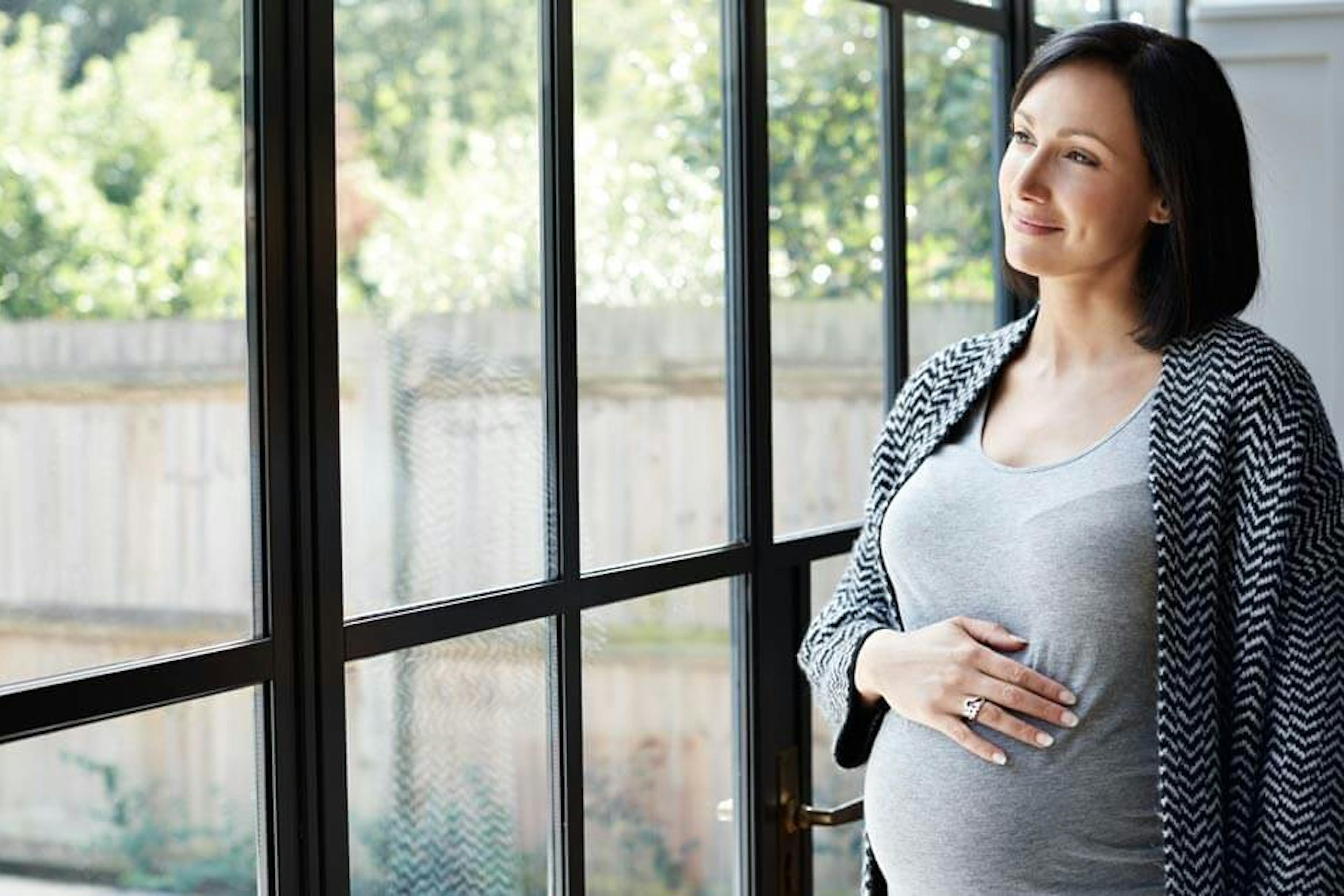 pregnant woman standing near window