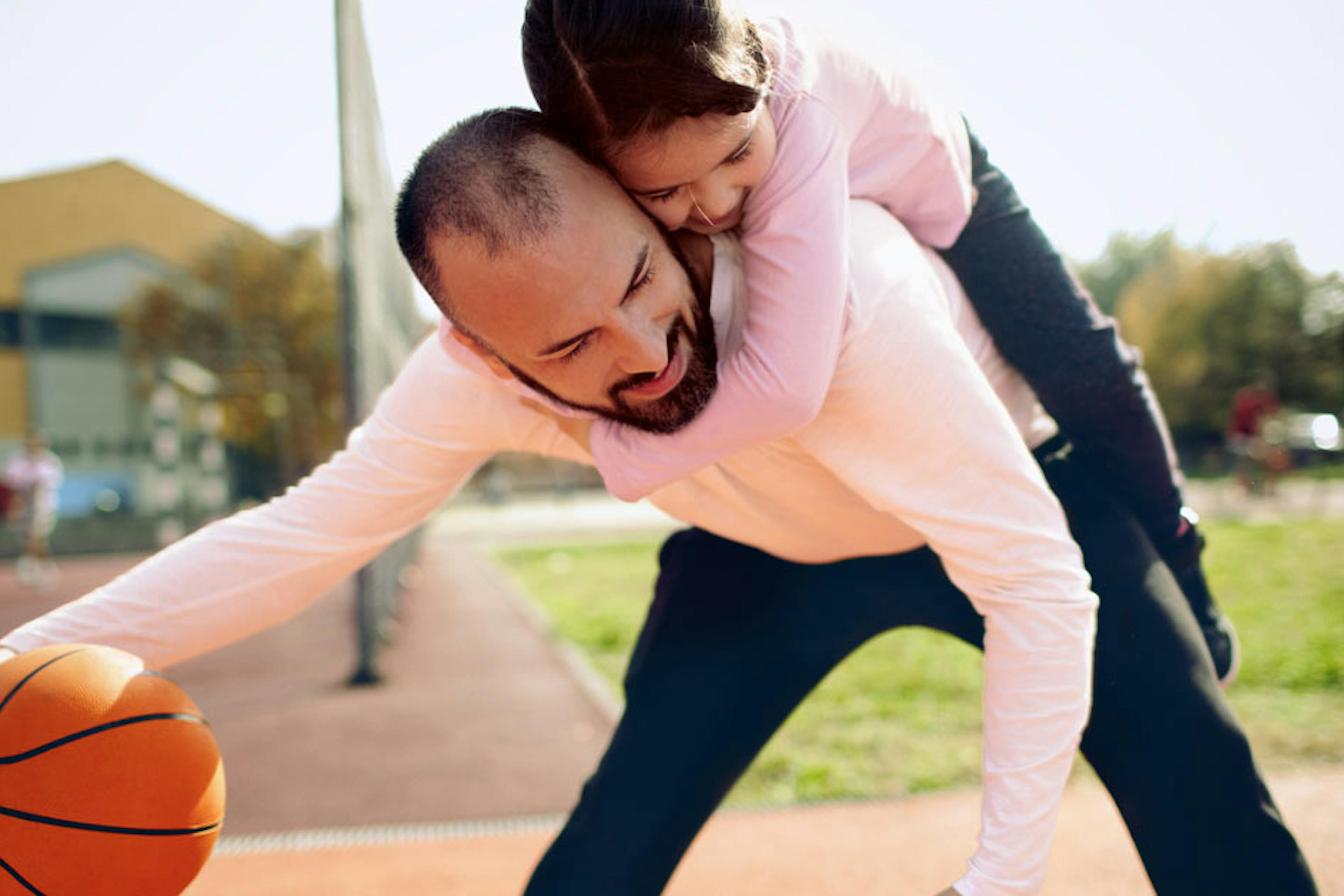 dad playing basketball with daughter