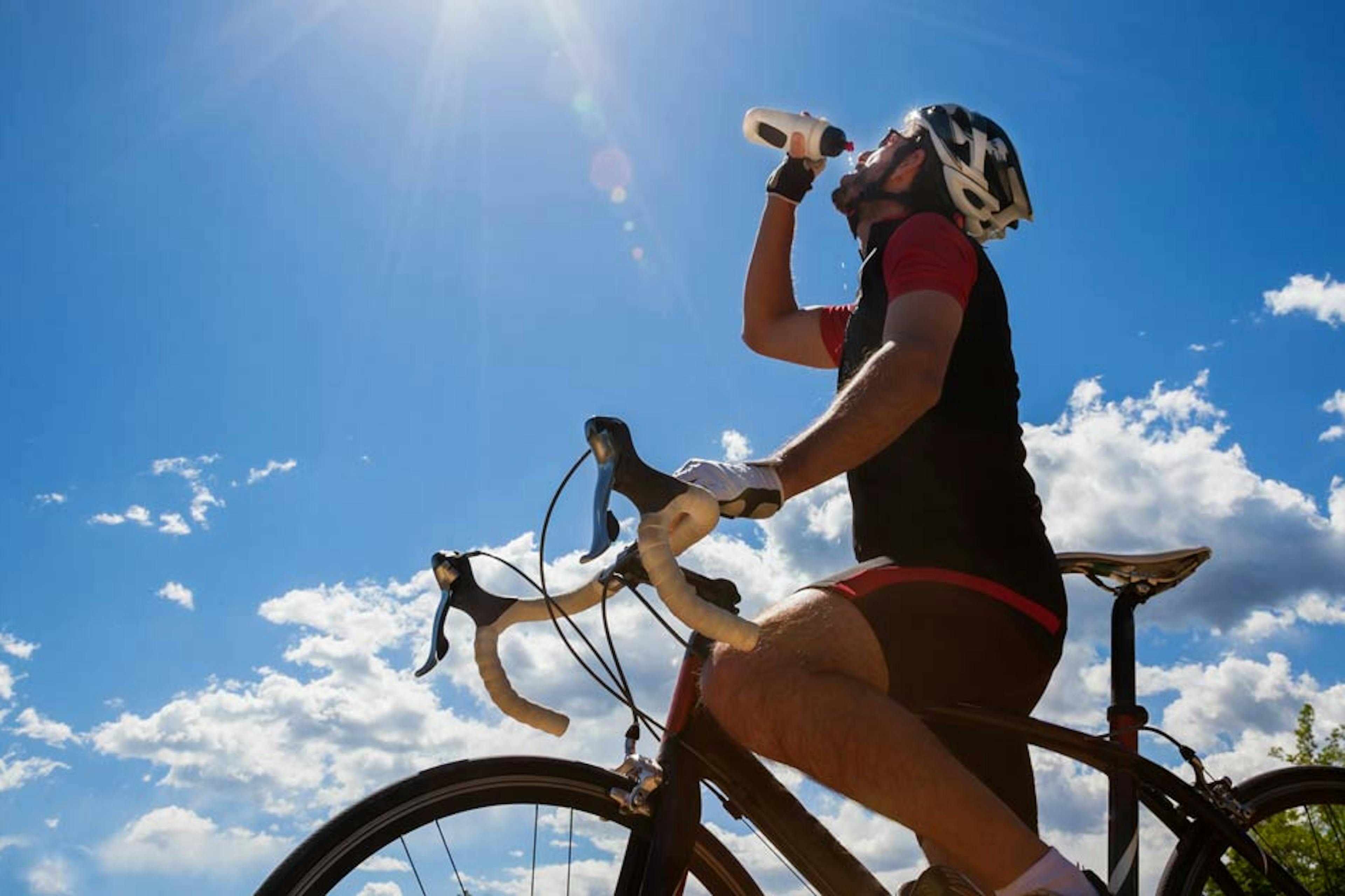 man on bike drinking water