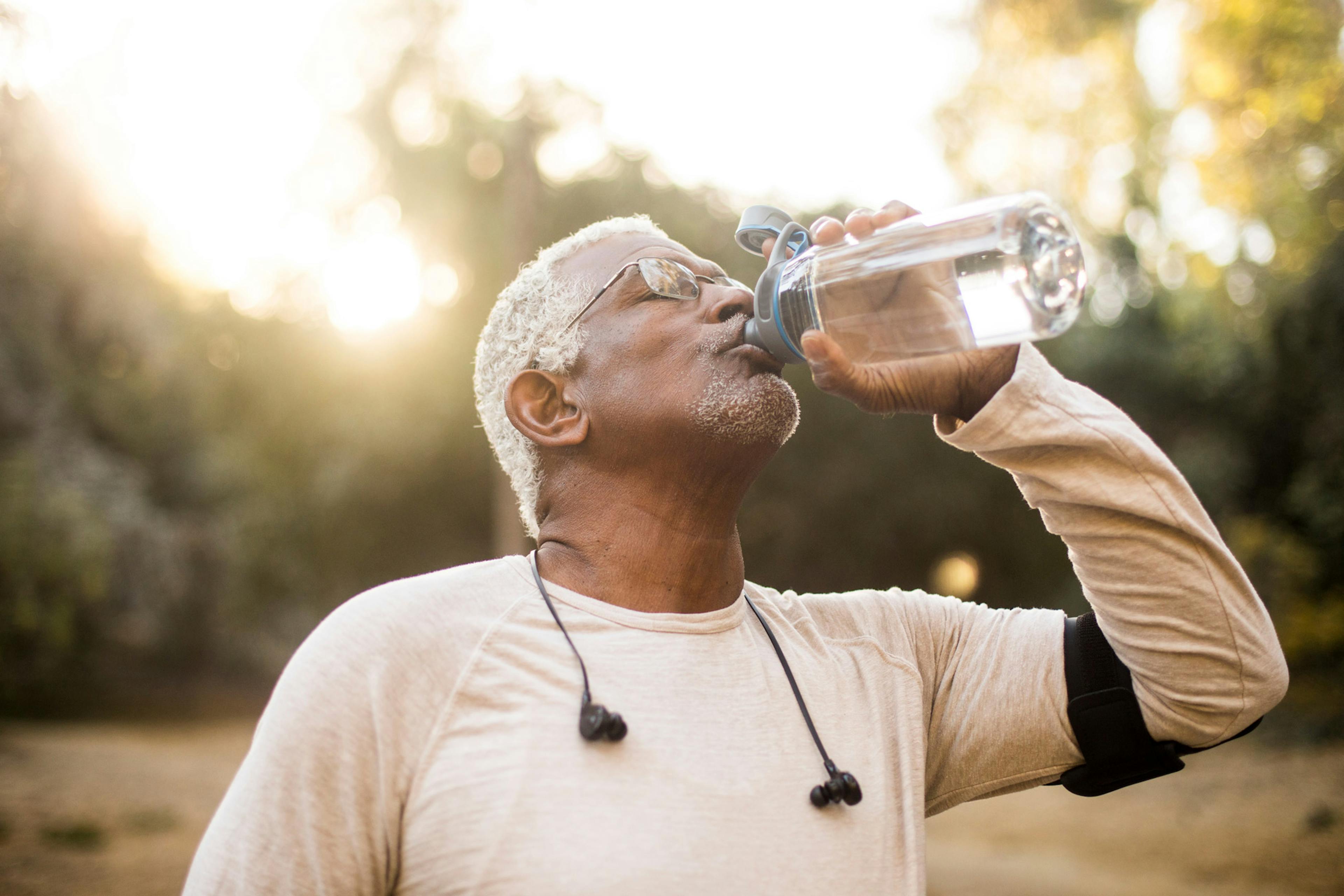 older man drinking water outside after a workout