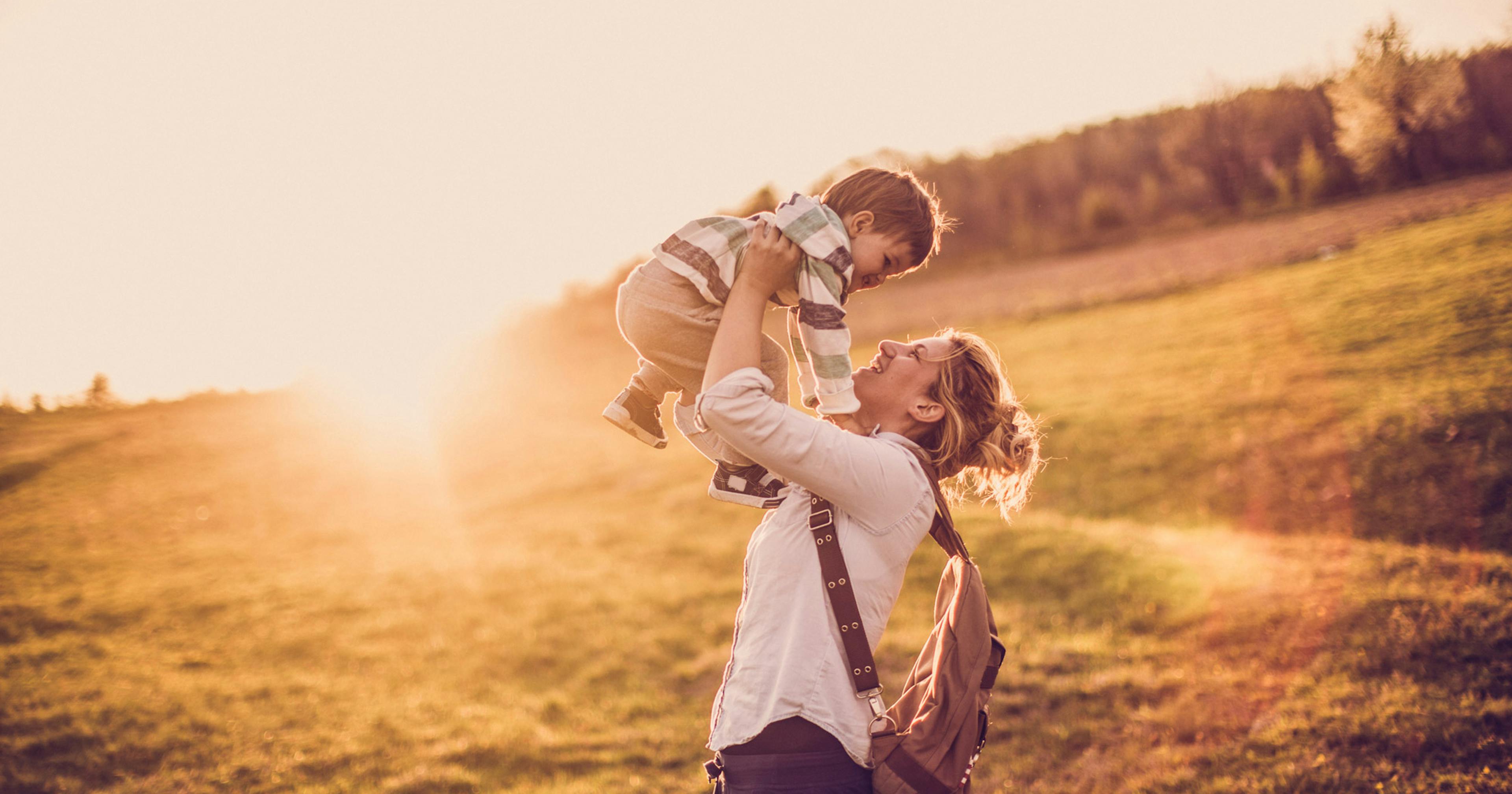 mom holding son above her head in the sunshine