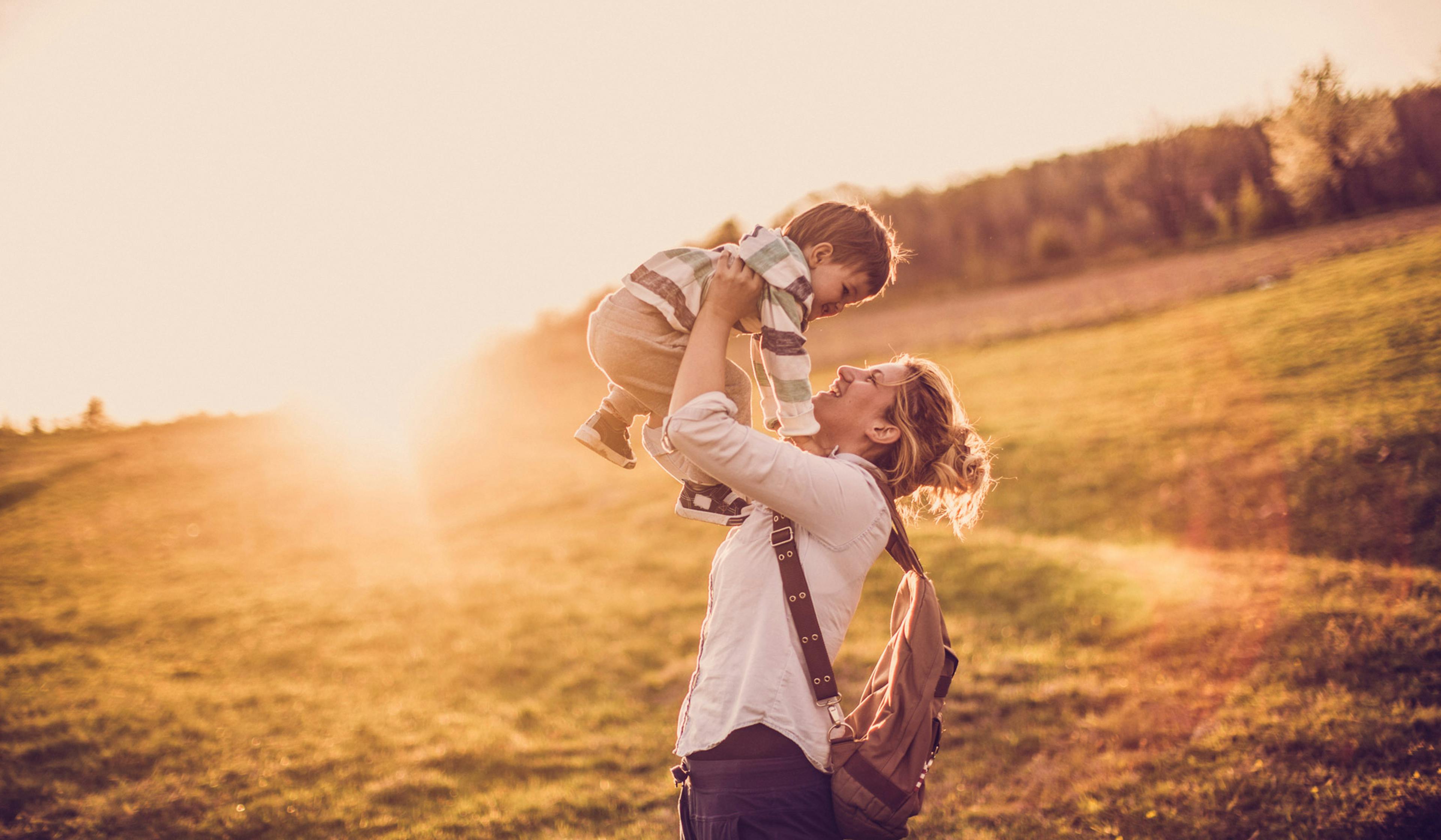 mom holding son above her head in the sunshine