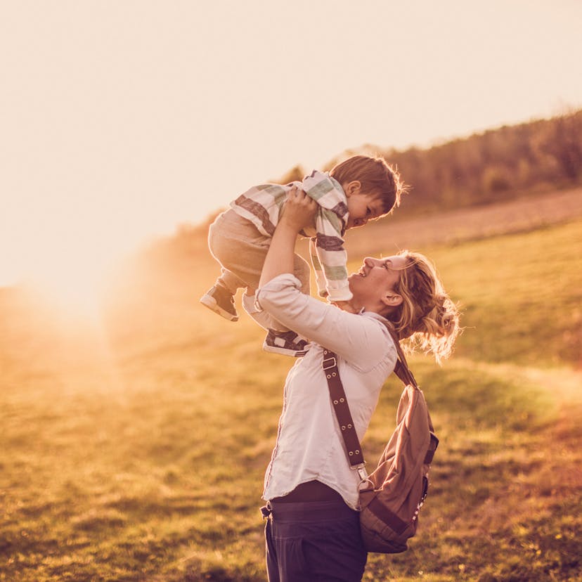 mom holding son above her head in the sunshine