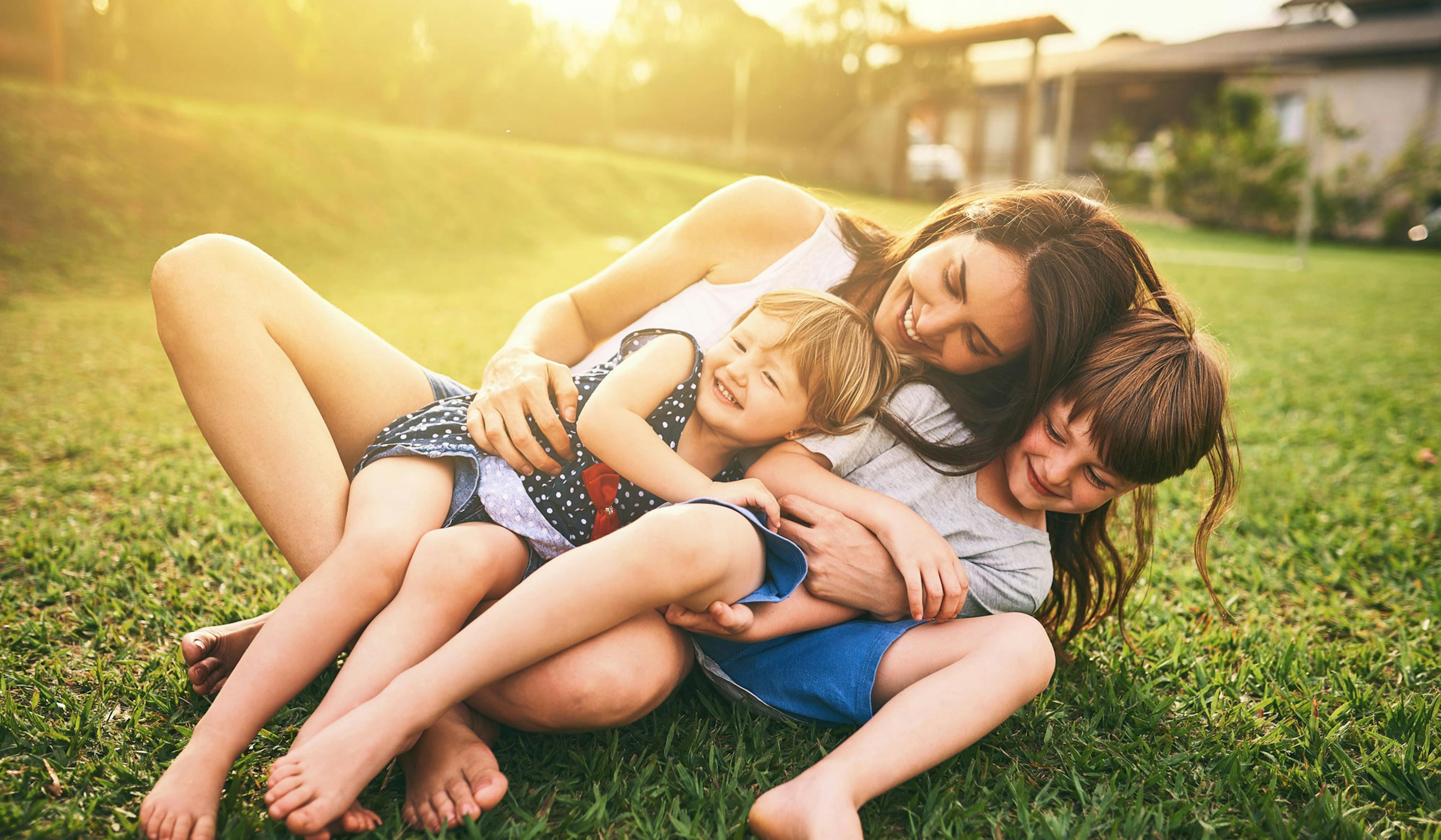 mom with daughter and son in grass, laughing