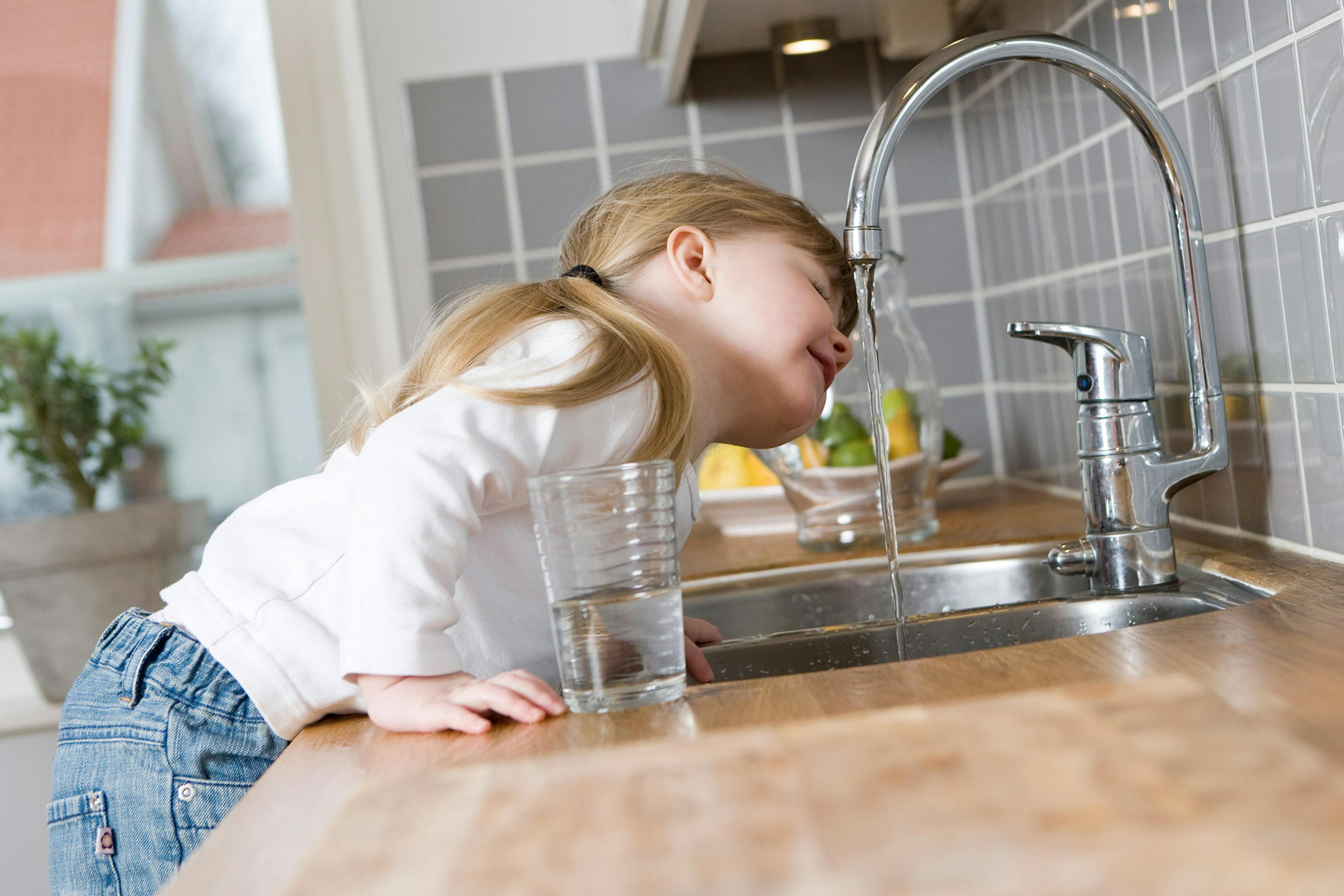 little girl drinking water from a faucet