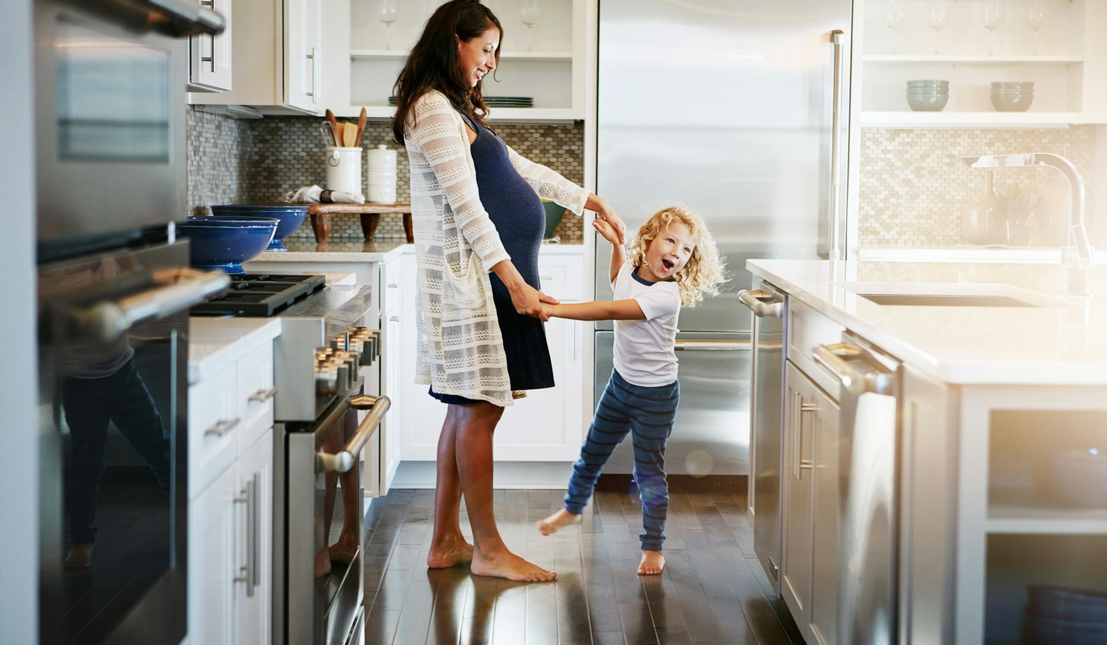 pregnant mom and son dancing in the kitchen