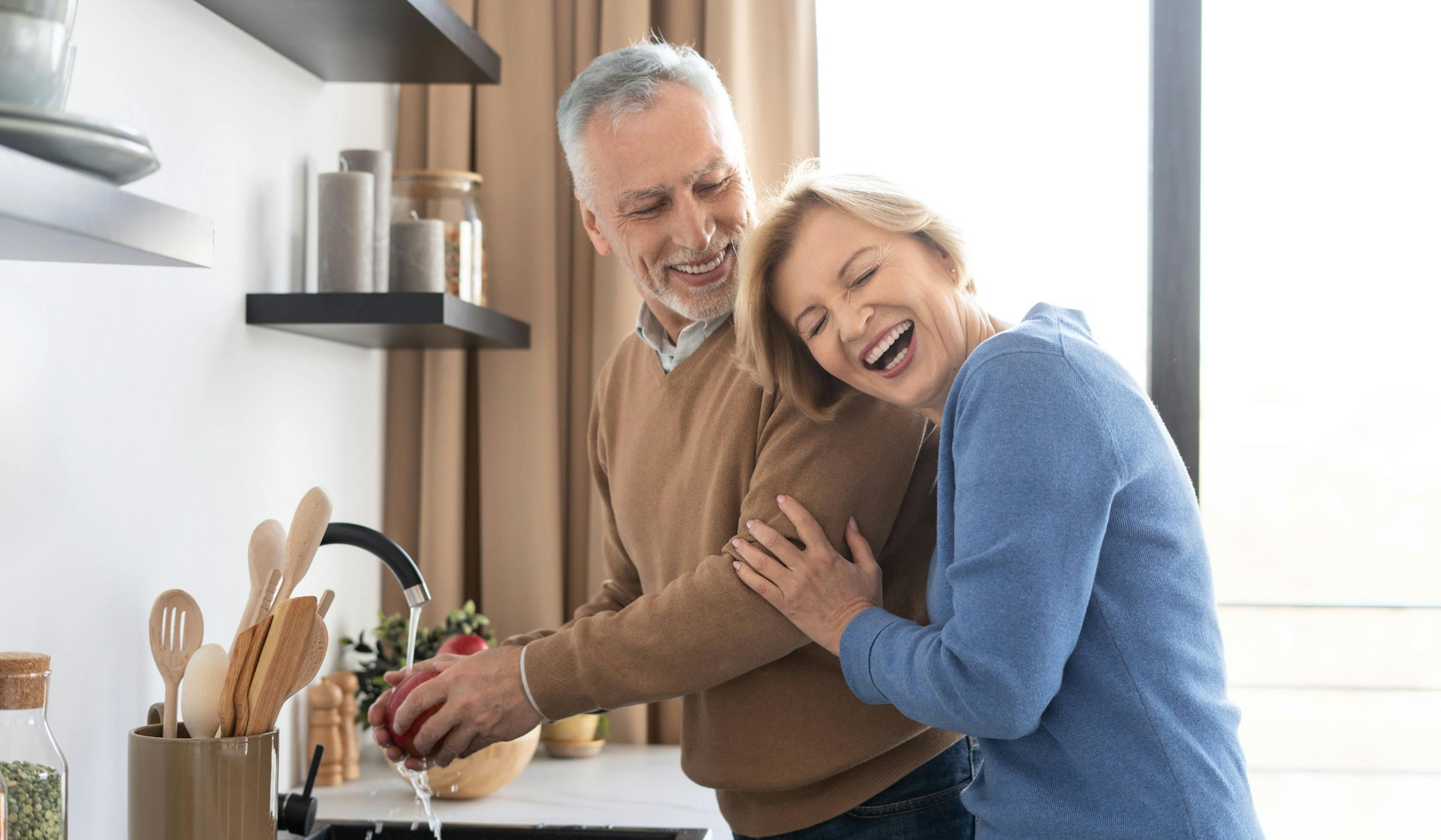 senior woman laughing with her husband in the kitchen