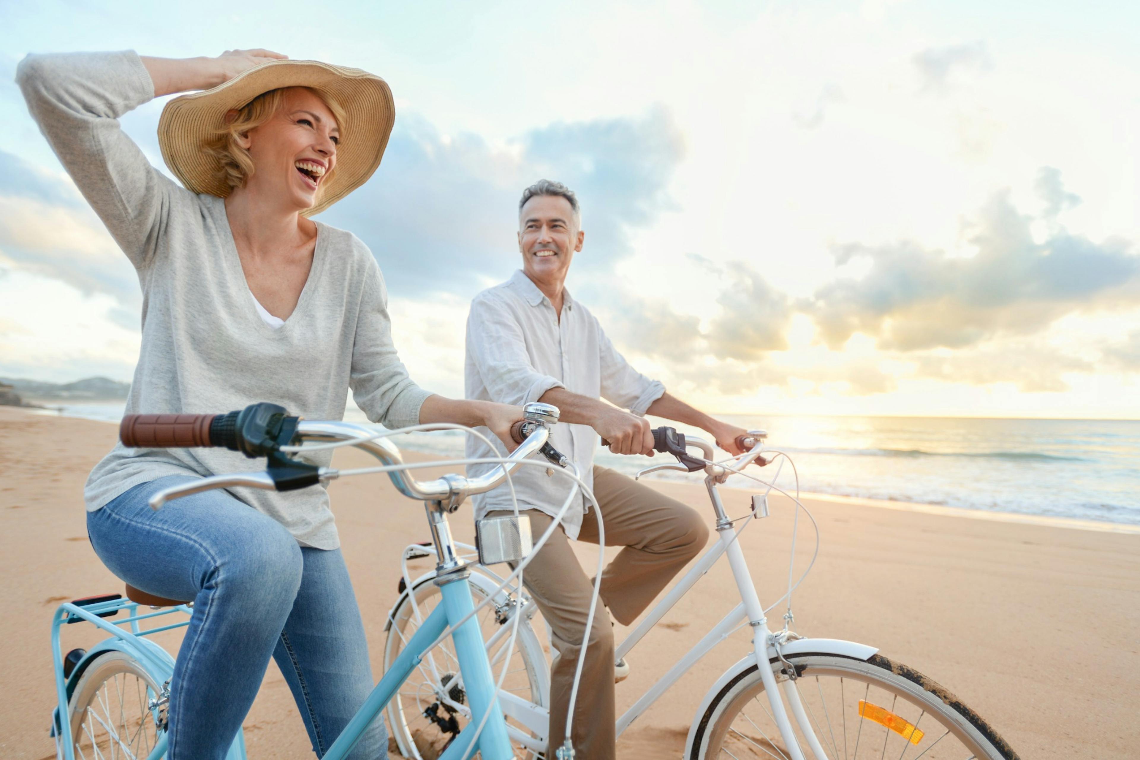 mature couple biking on the beach