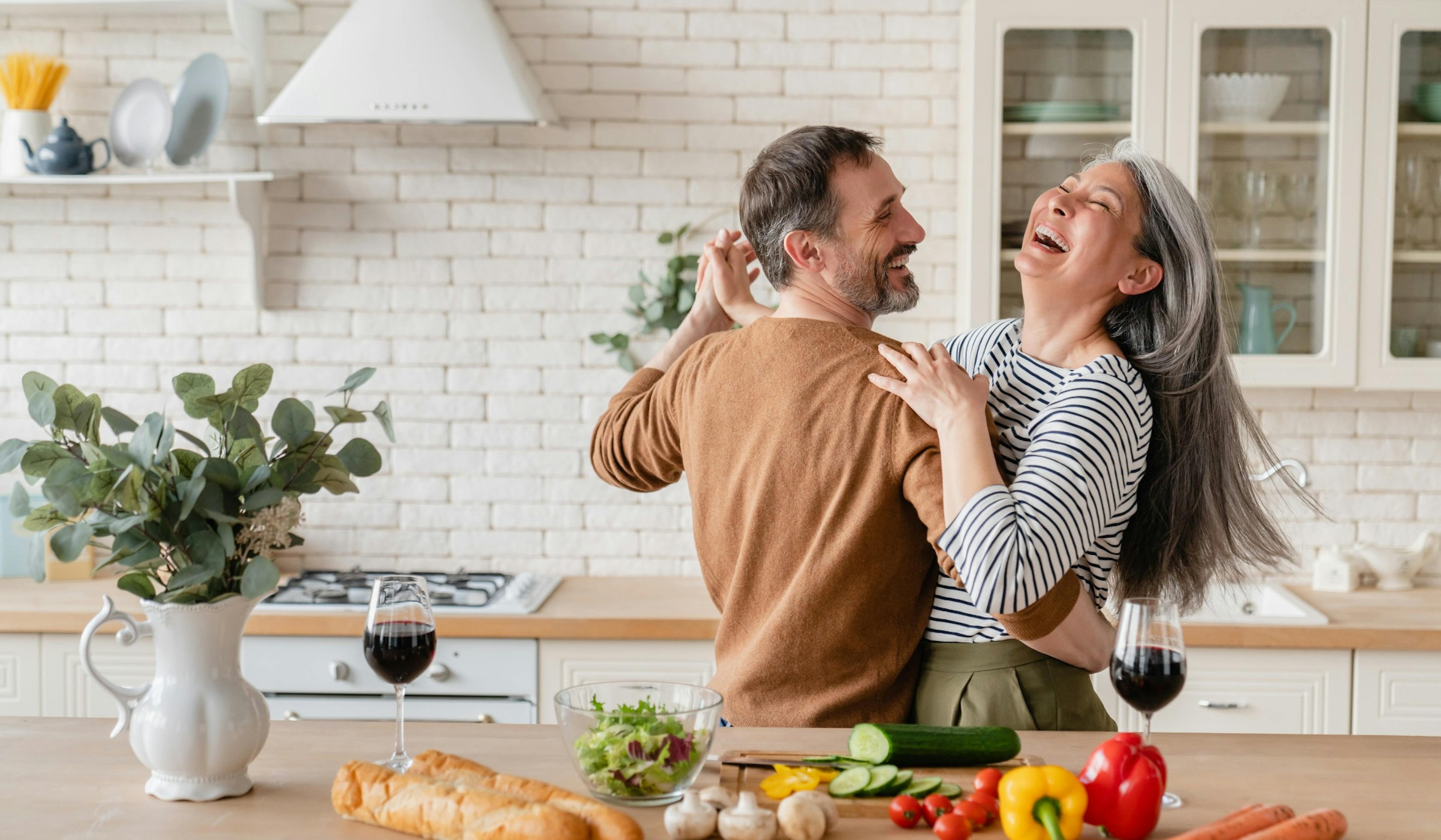 happy cheerful middle aged couple dancing in the kitchen