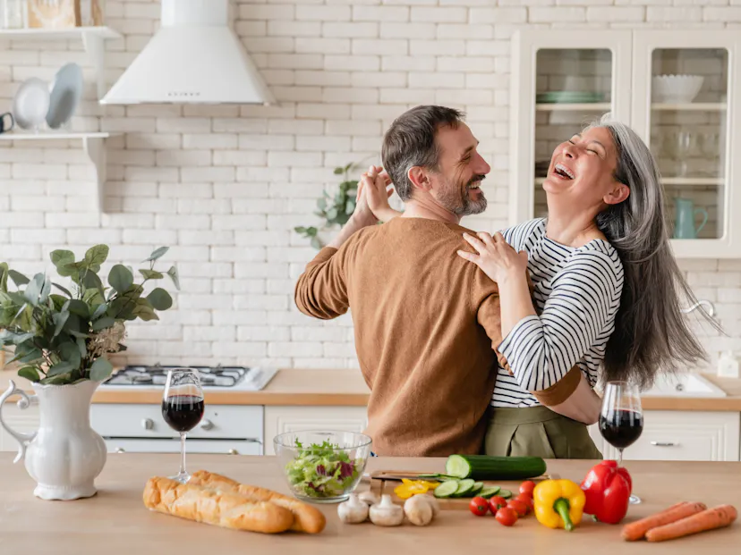 happy cheerful middle aged couple dancing in the kitchen