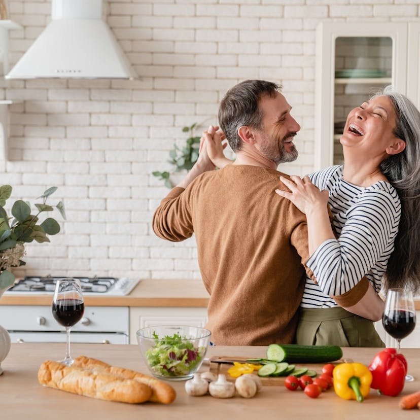 happy cheerful middle aged couple dancing in the kitchen