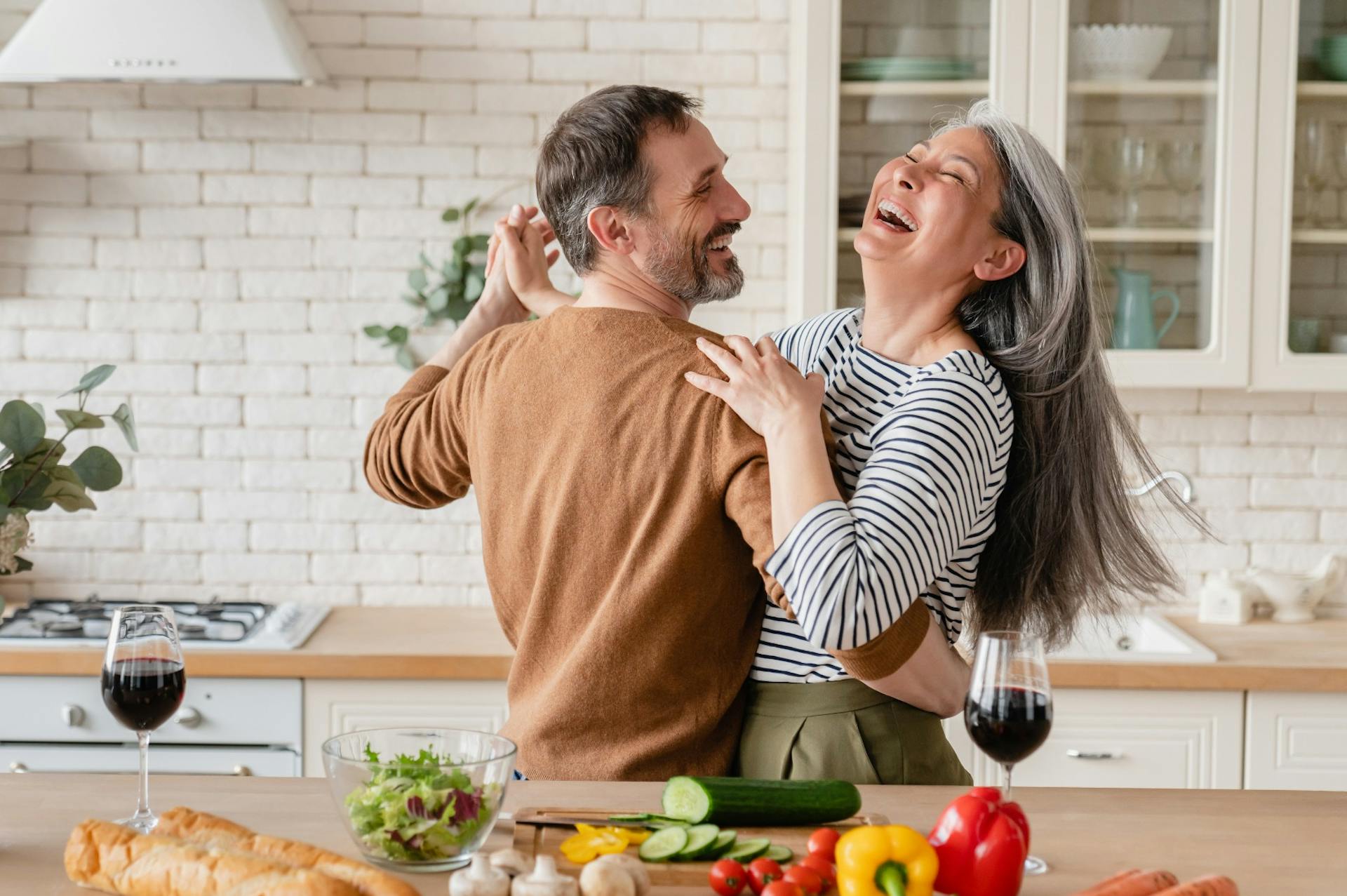 happy cheerful middleaged couple dancing in the kitchen