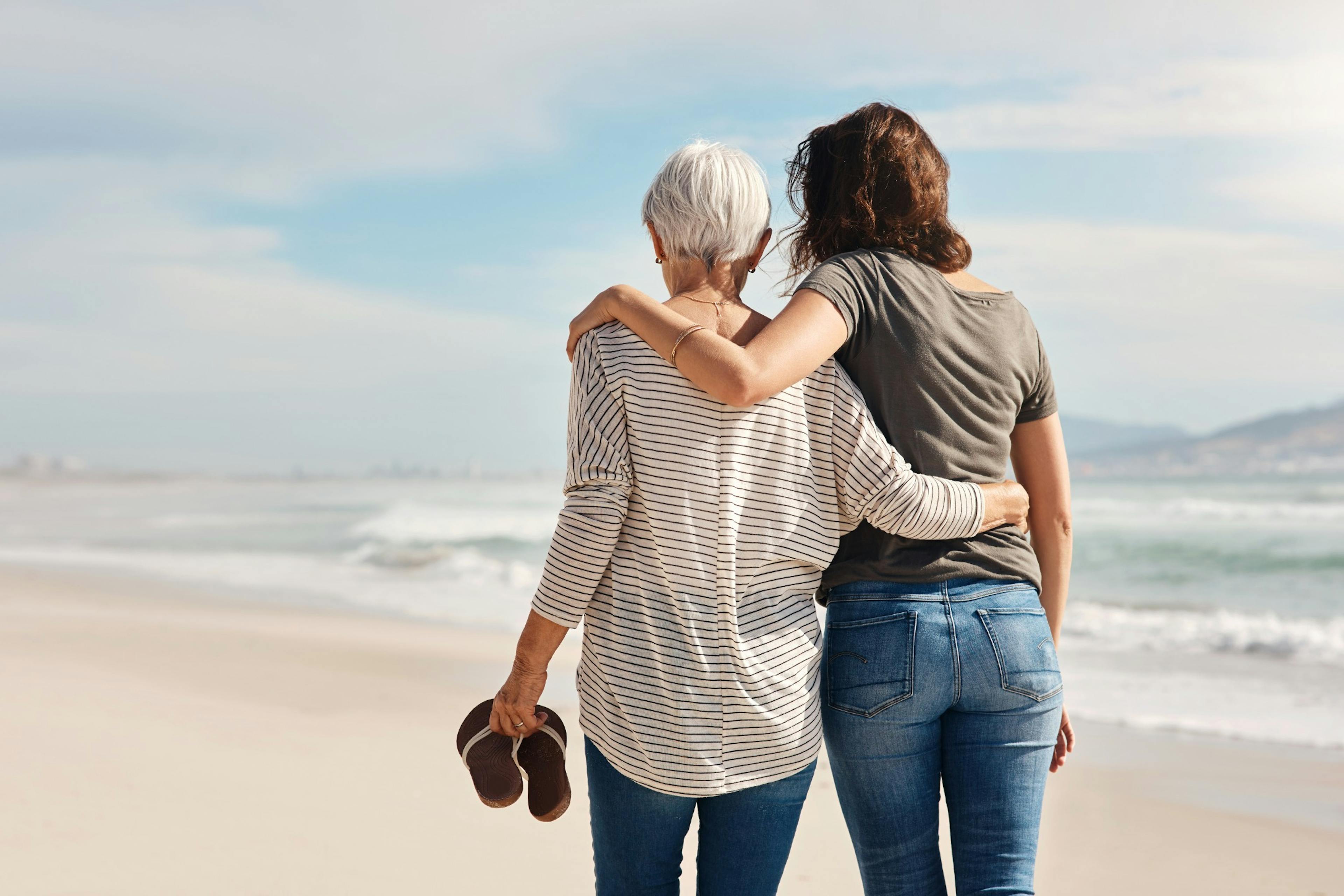 mom and middle age daughter walking on the beach