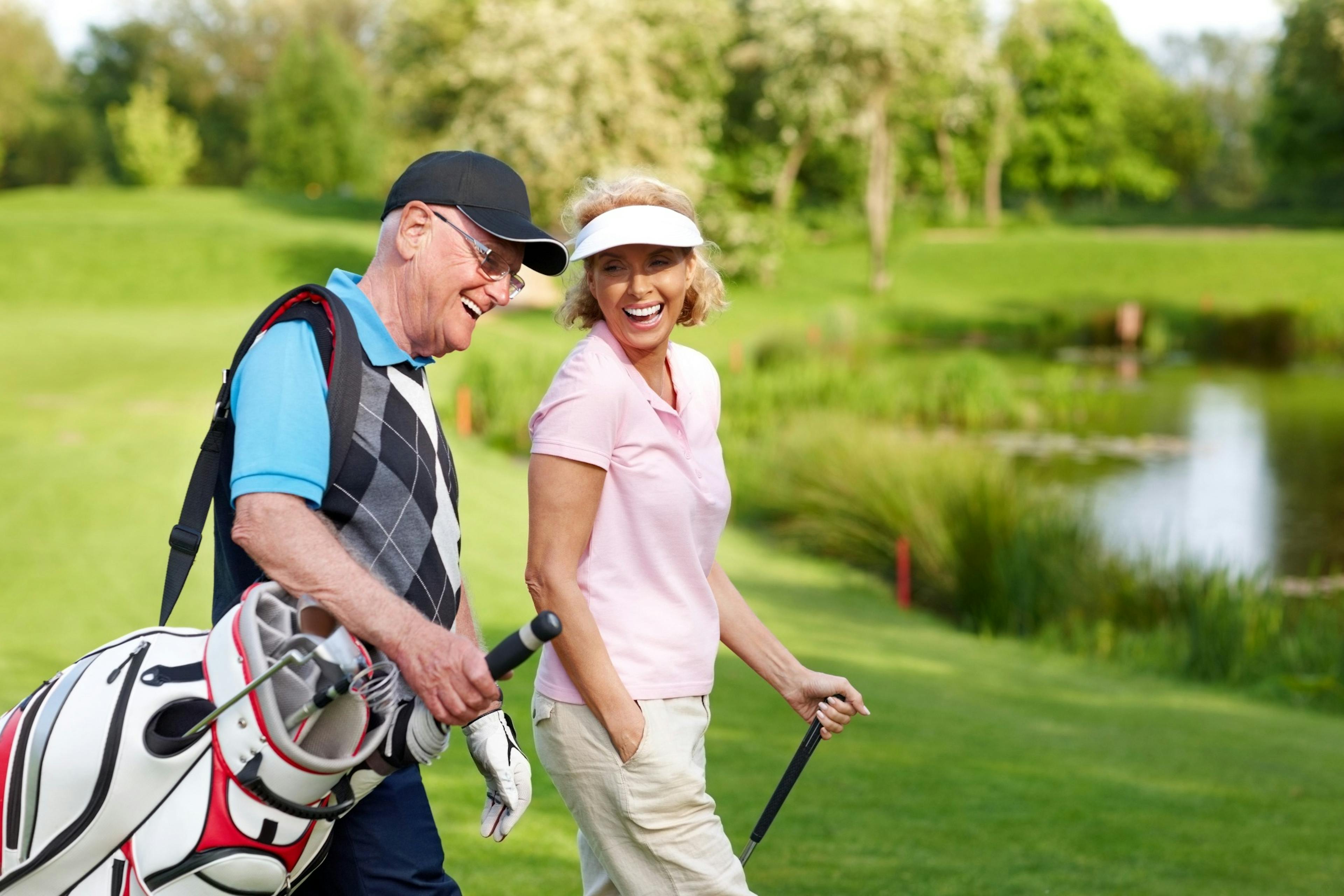 cheerful middle age couple playing golf