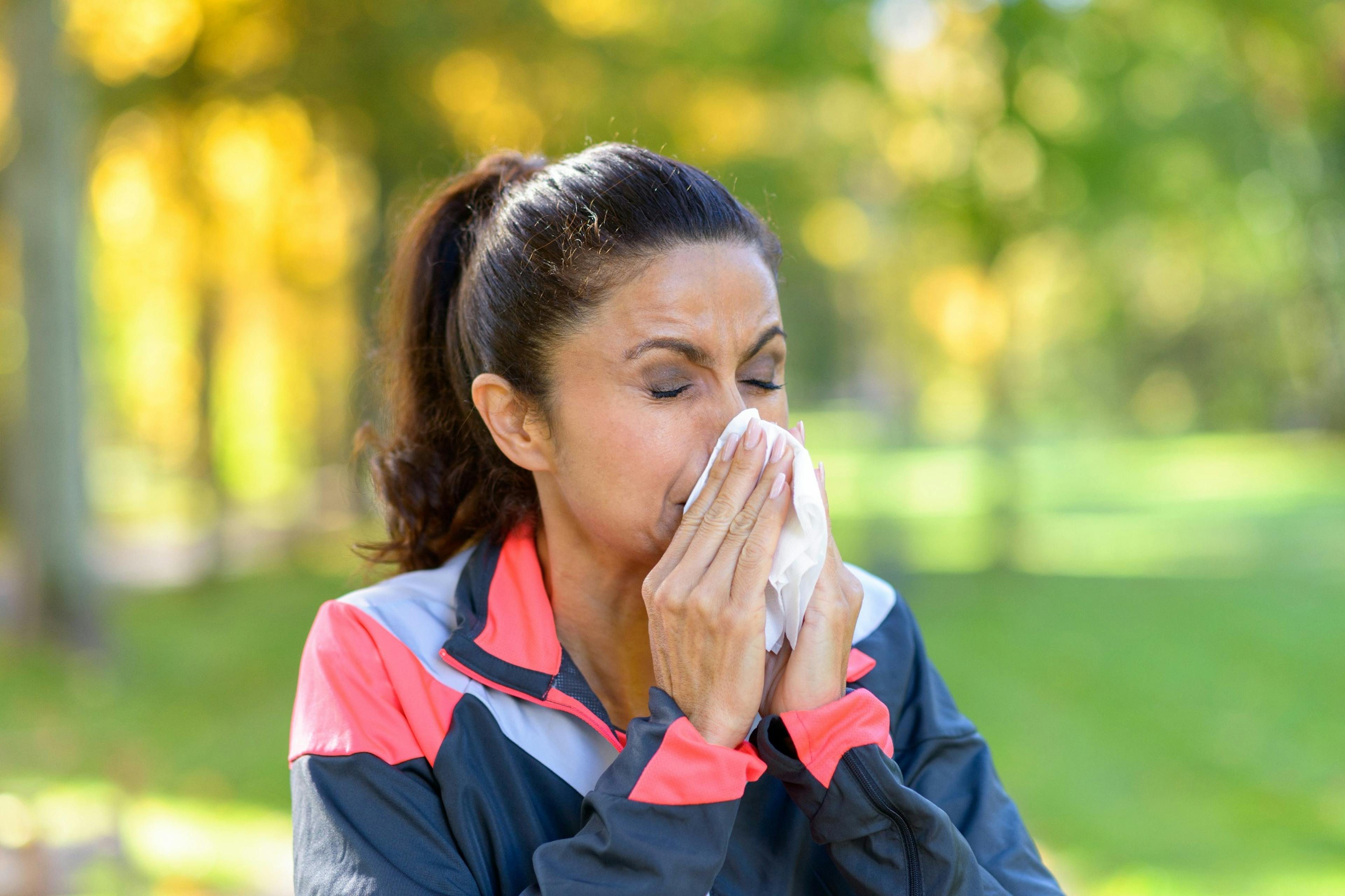 woman blowing nose while working out outside