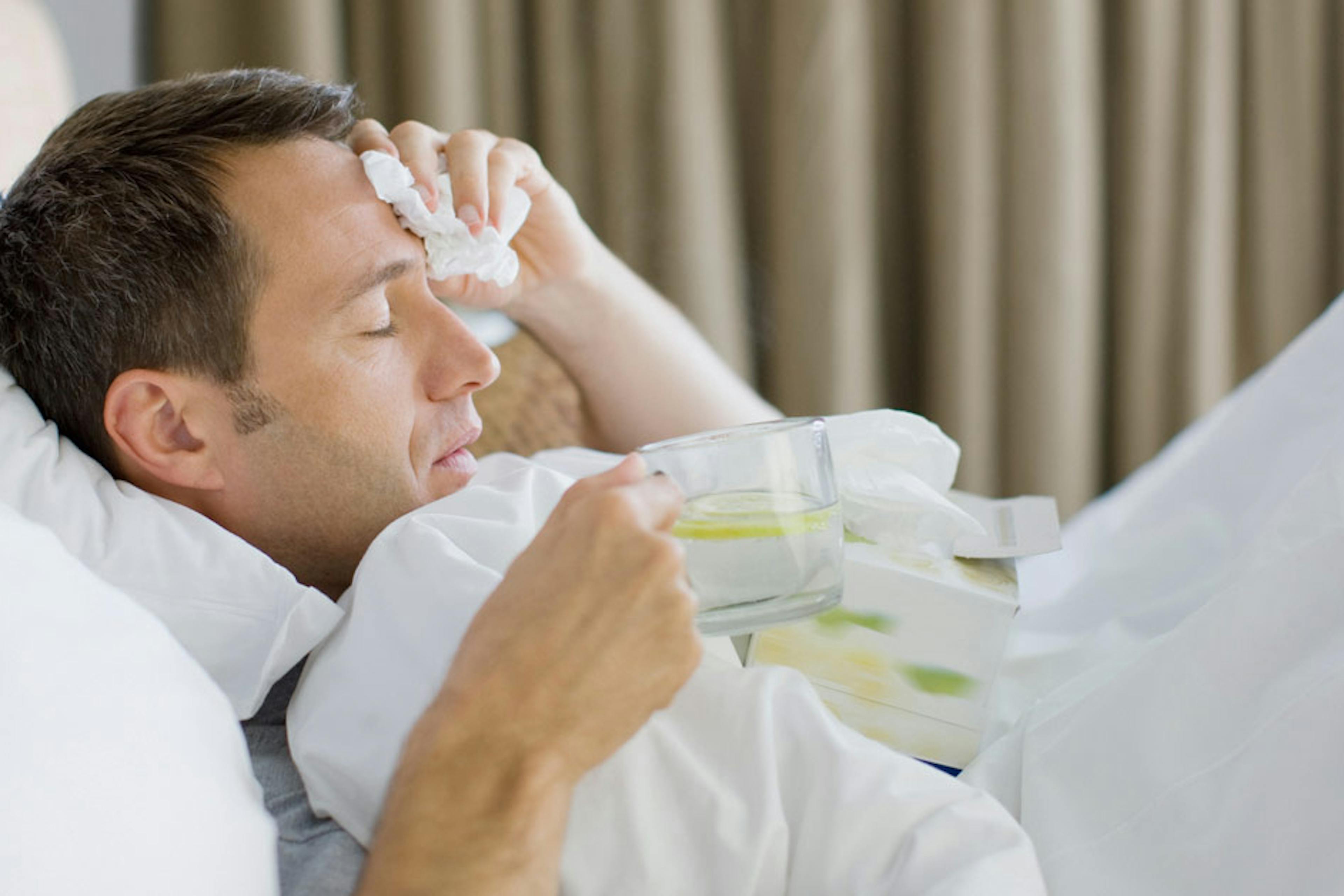 man sick in bed with tea