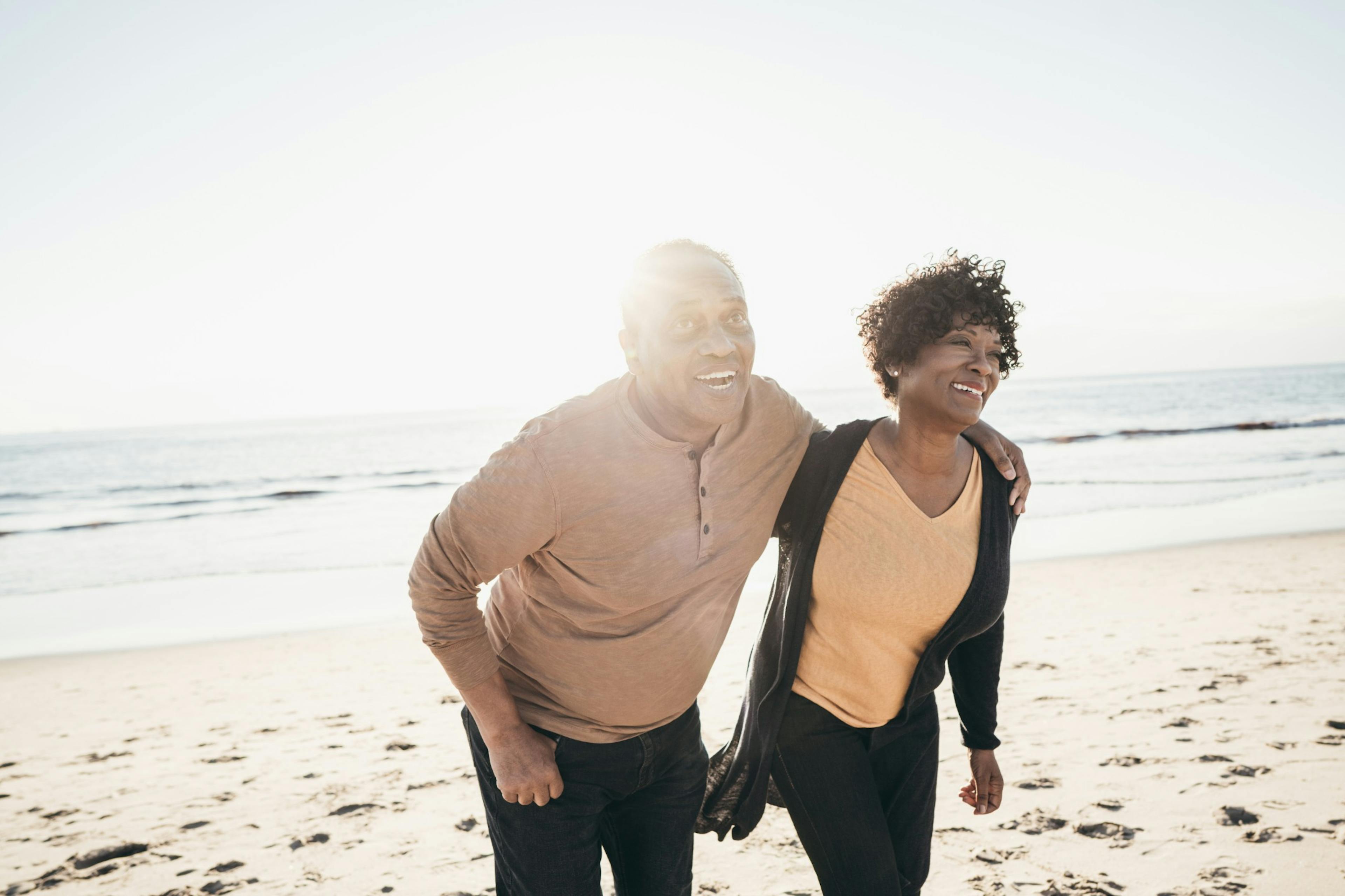 middle age couple smiling and walking on the beach