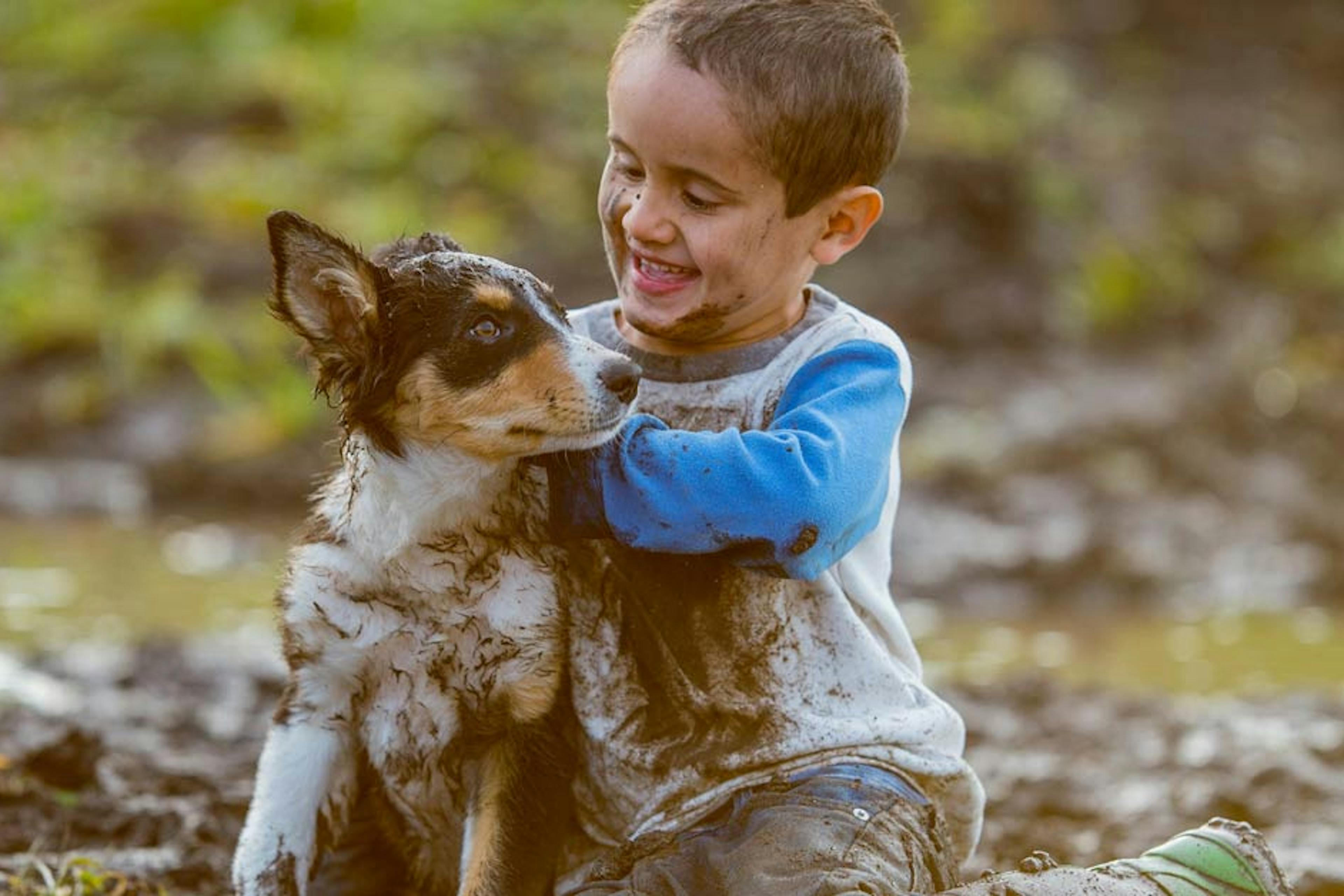 boy and puppy playing in the mud