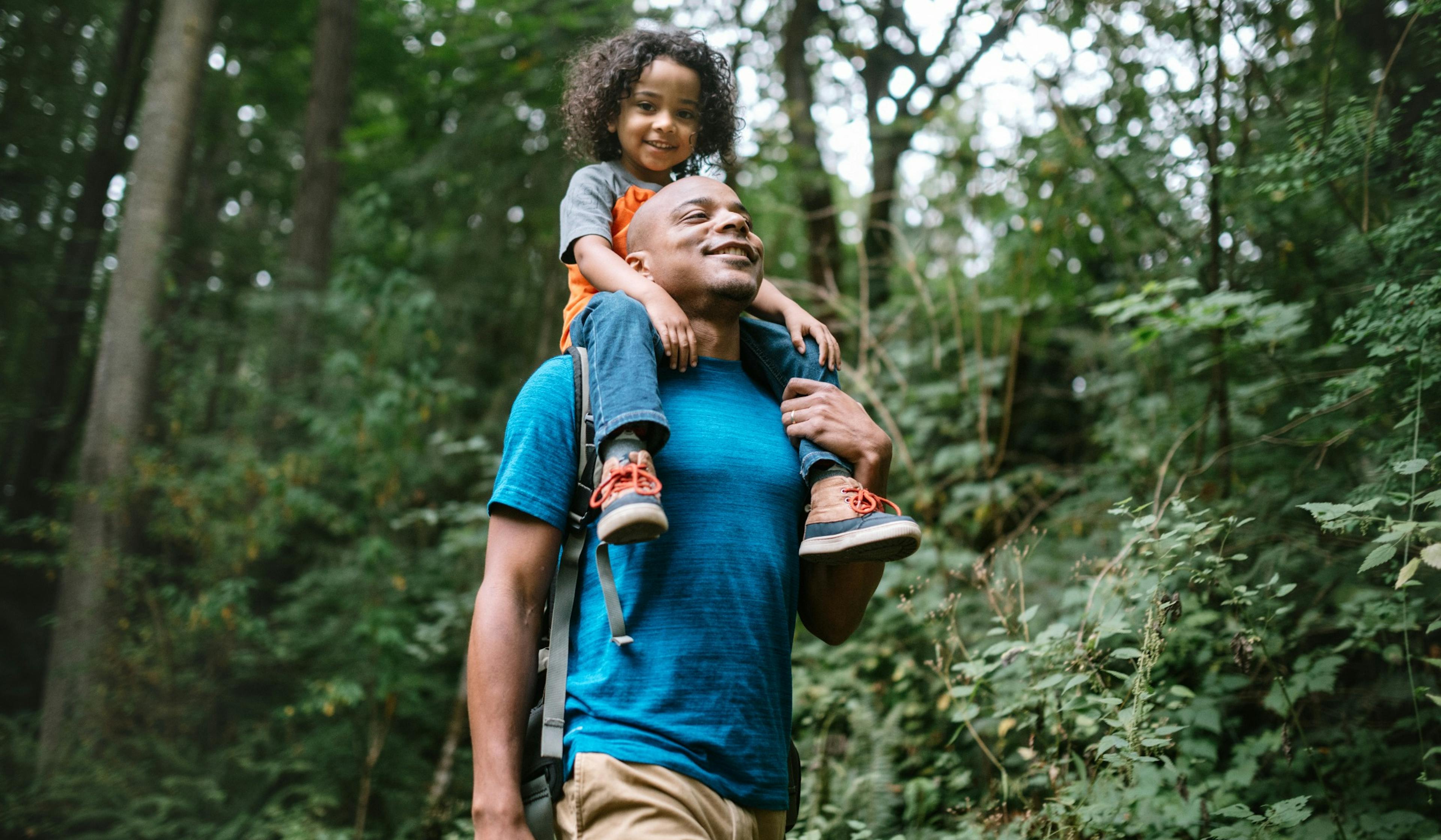 father carries son on hike