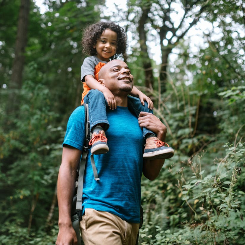 father carries son on hike