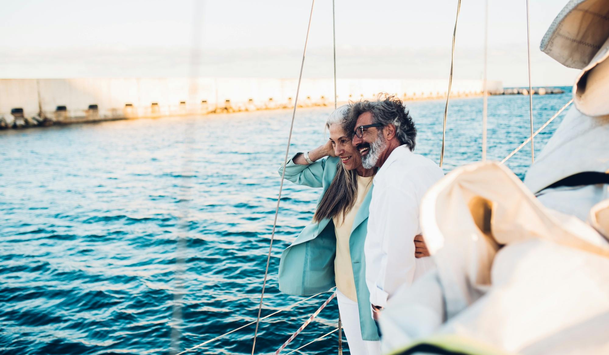 Senior couple watching the coast from their sailboat and enjoying