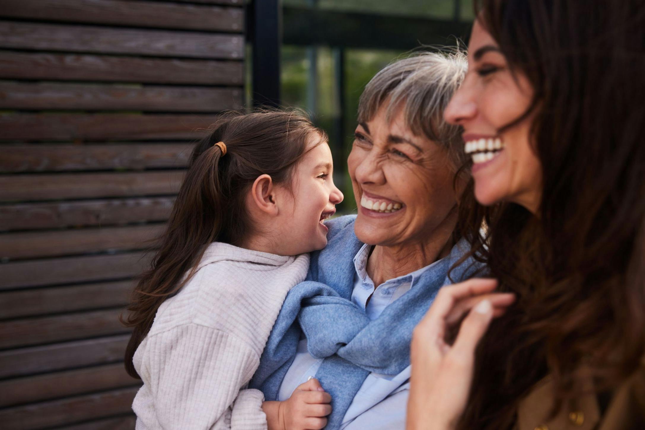 Laughing little girl standing outside with her grandmother