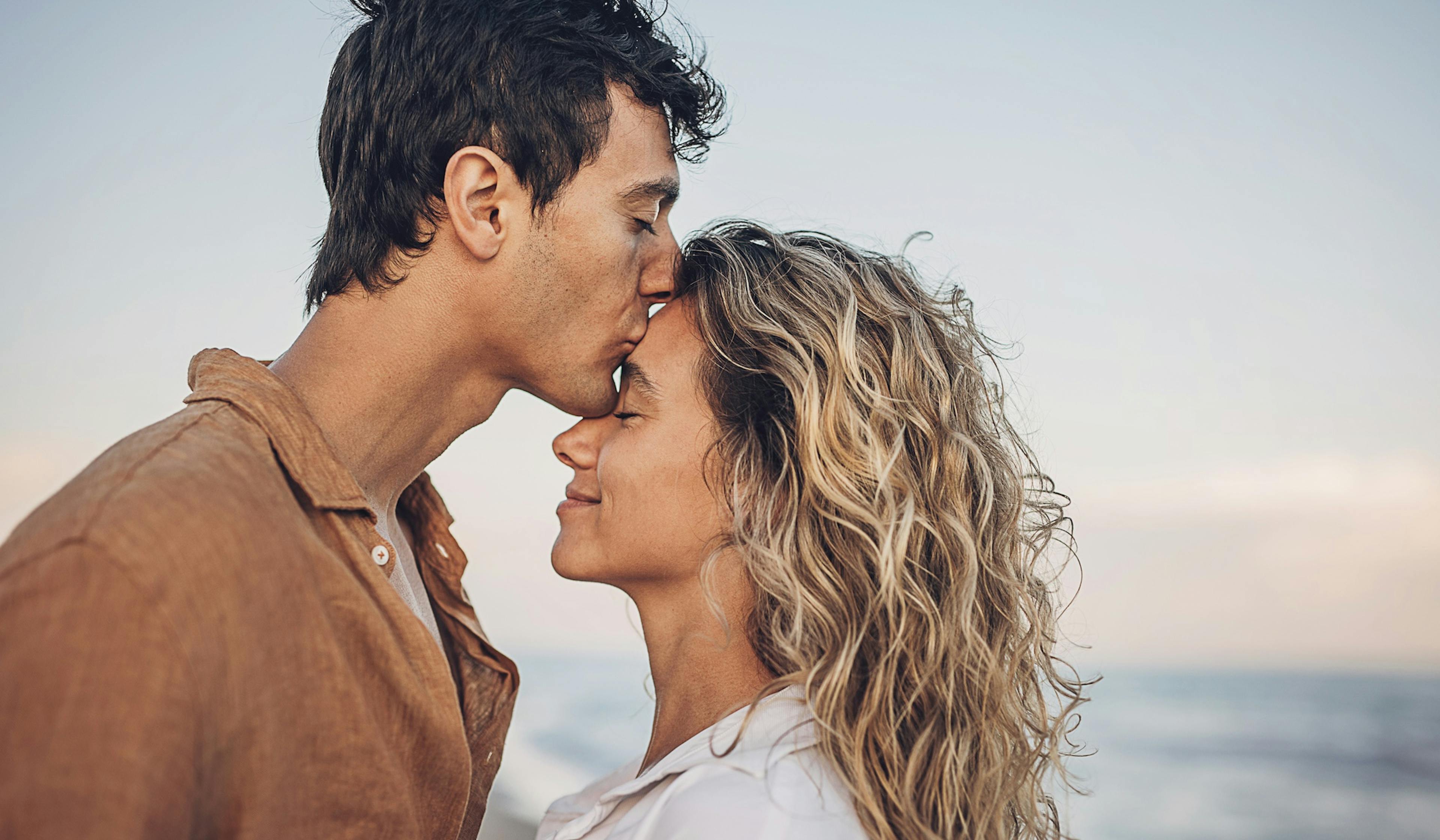 man kissing woman's forehead