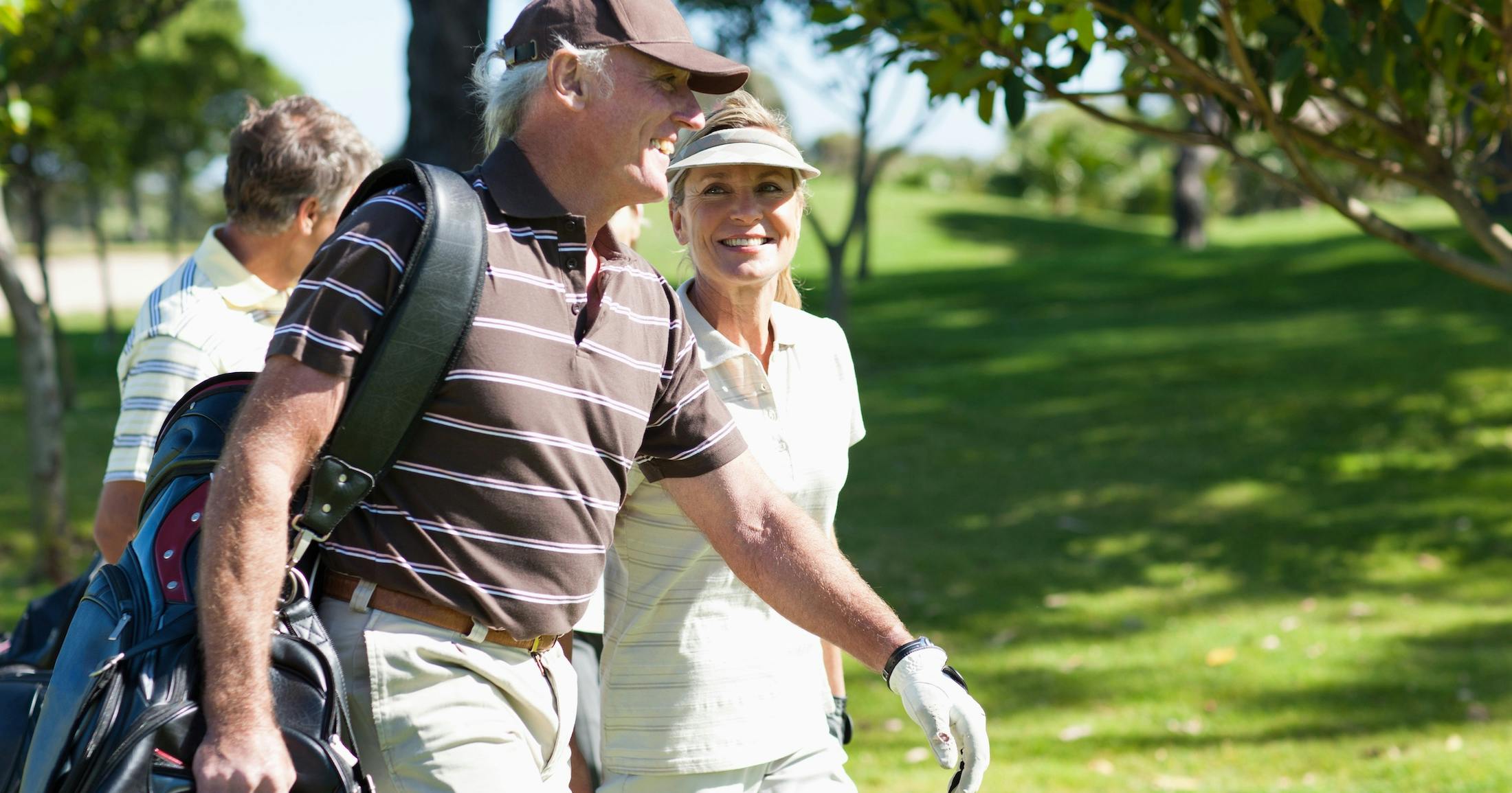 Mature couple carrying golf bags