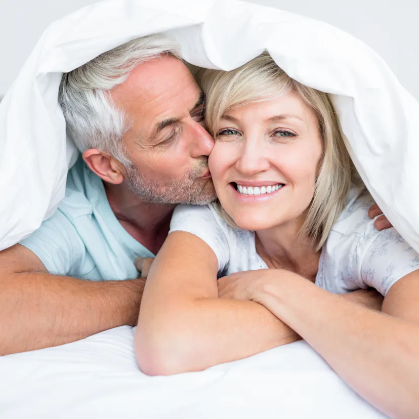 mature man kissing womans cheek in bed