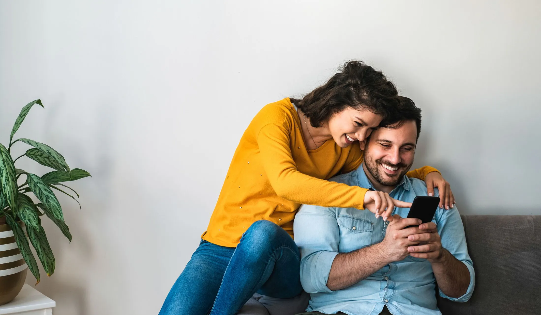 happy couple at home looking at phone