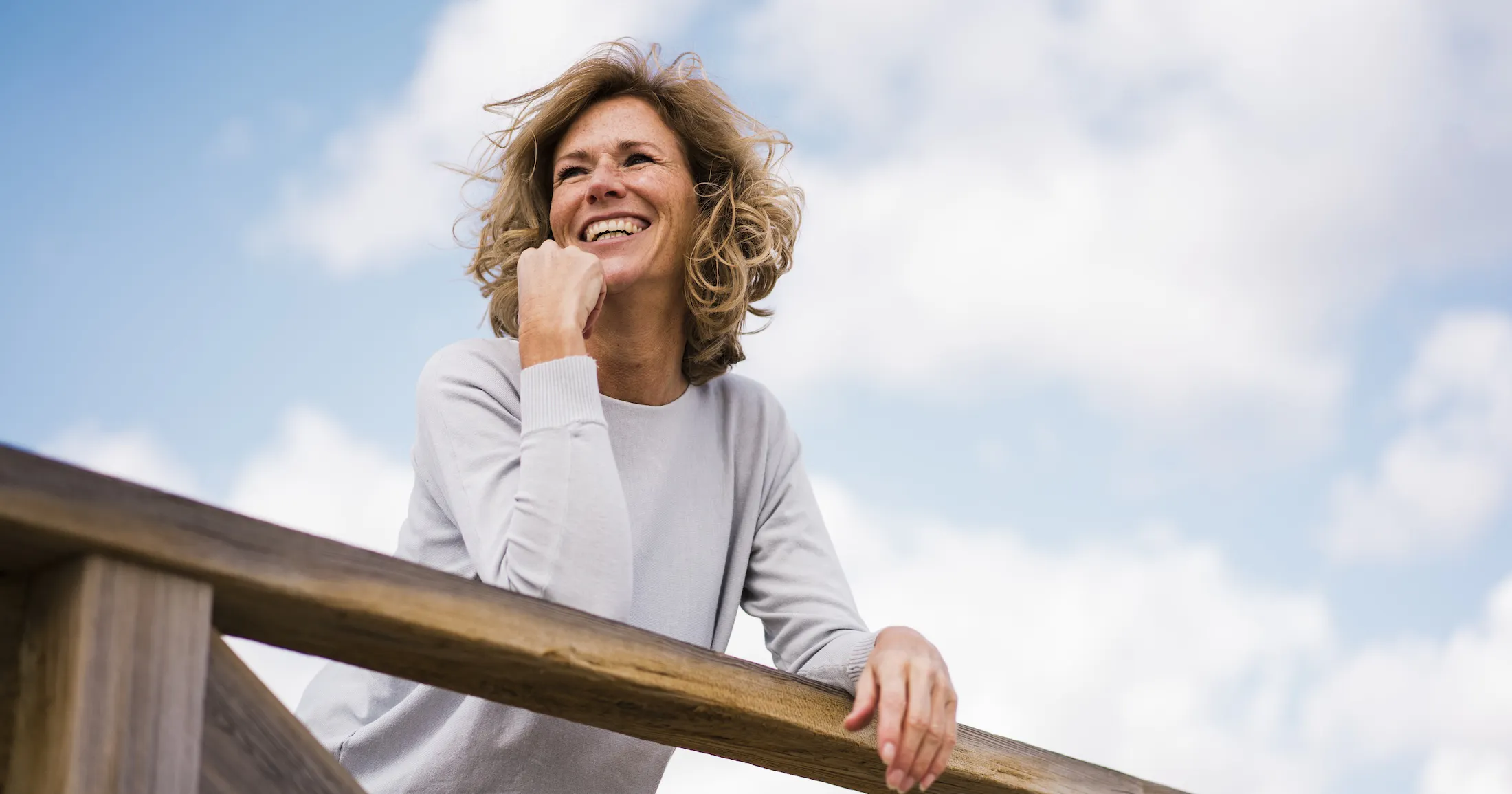 Happy mature woman leaning on railing