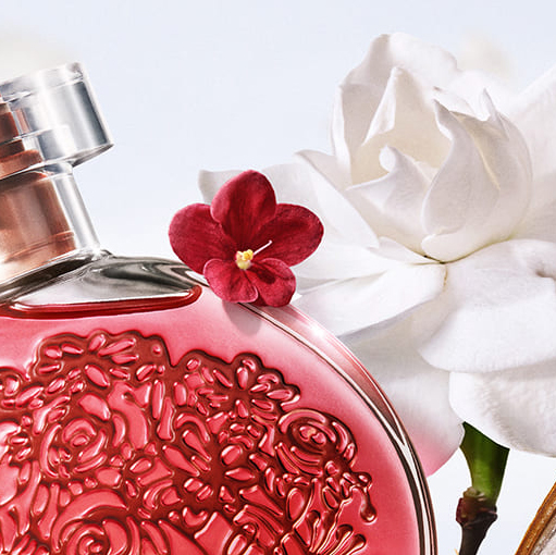 Um frasco vermelho de perfume com uma flor.