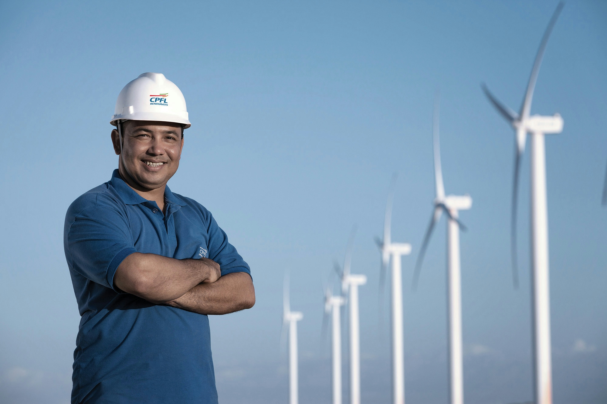 Homem de braços cruzados na frente de aerogeradores